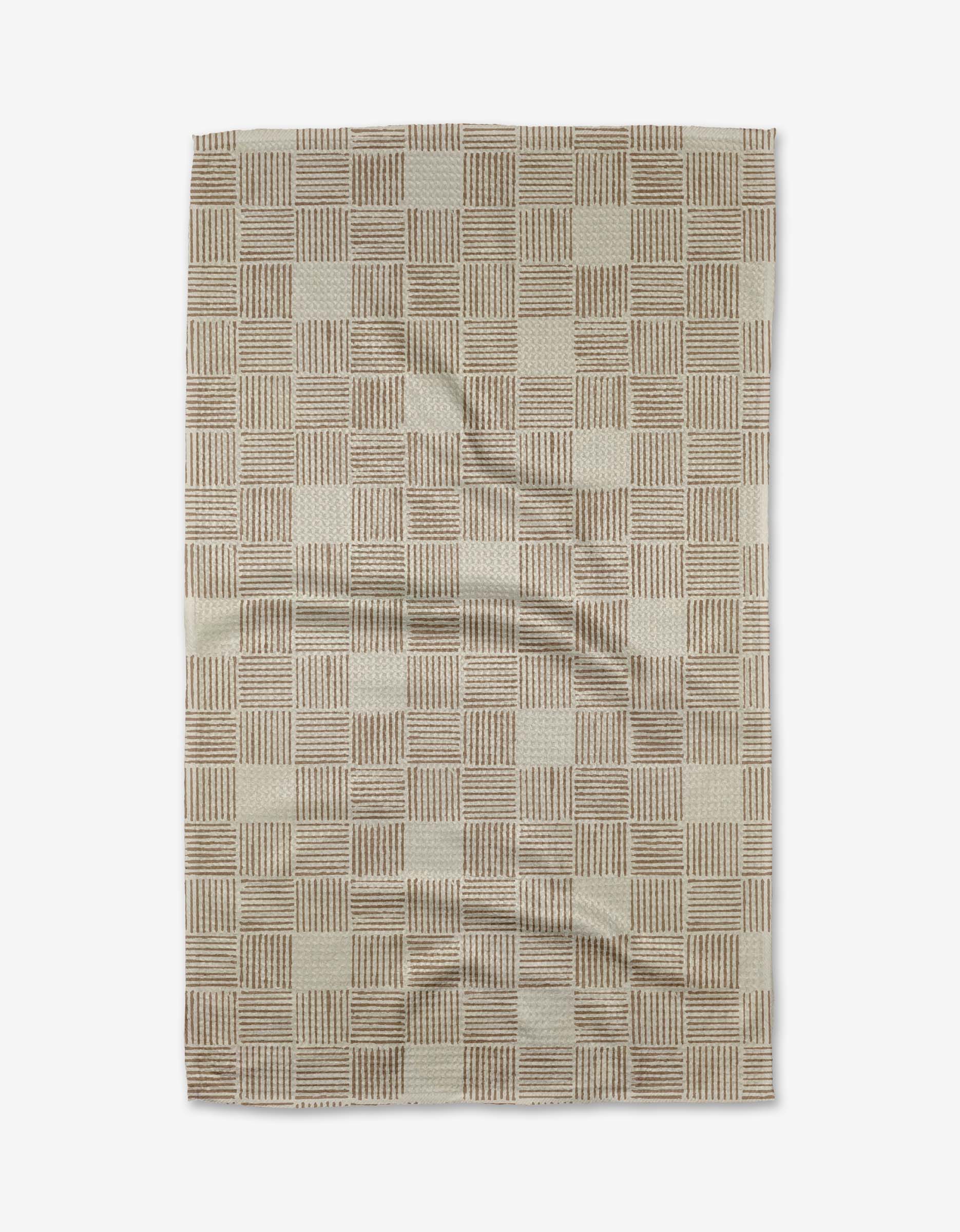 The Thatcher Tea Towel by Studio Jeannot is a rectangular beige and brown towel with a checkered pattern of small squares and stripes, made from ultra-absorbent Geoweave™ fabric for superior performance. Wrinkles are visible when laid flat.