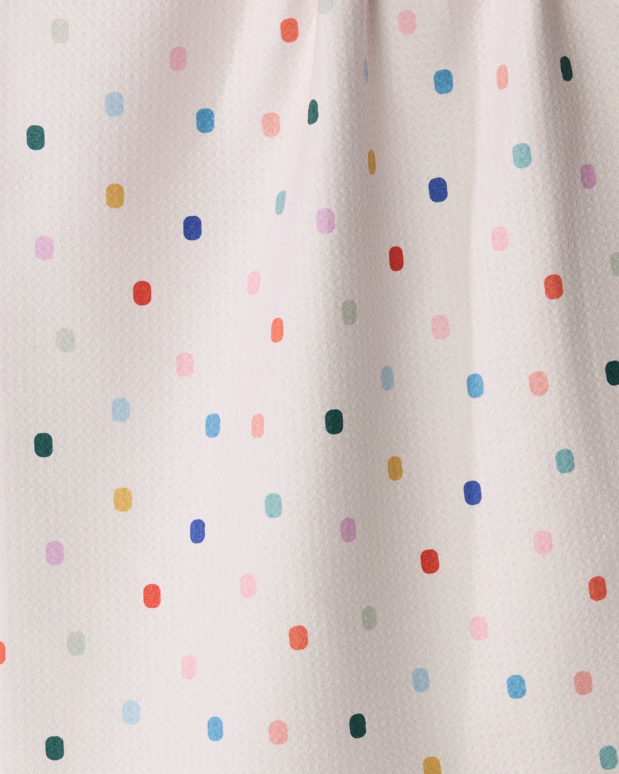Introducing the Tile Shuffle kitchen towel from Geometry—a charming and practical addition to your daily routine. Featuring a white background adorned with colorful polka dots in red, blue, green, yellow, purple, and orange arranged in a loose grid pattern, this towel showcases slight folds and a subtle textured surface for both visual appeal and everyday functionality.