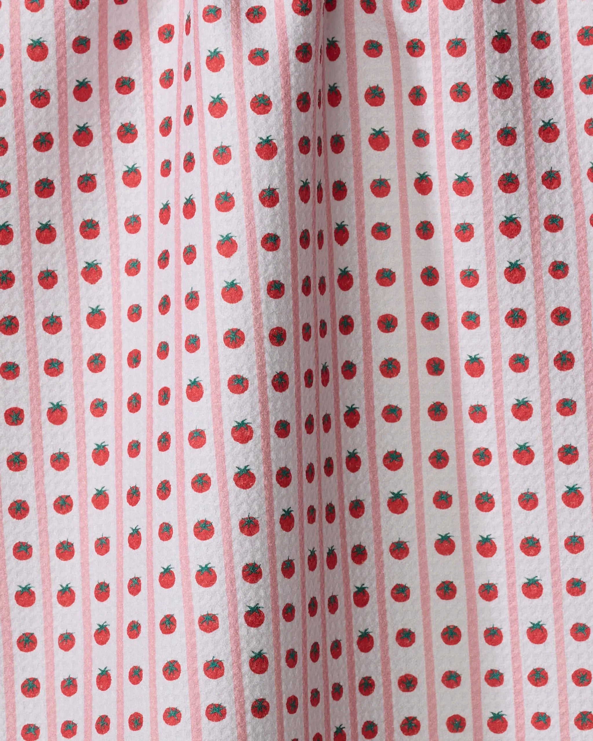 A close-up of Brittany Jepsen’s Tomato Stripes tea towel showcases small red tomatoes in neat rows on a white background with pale pink stripes. The ultra-absorbent fabric appears softly wrinkled.