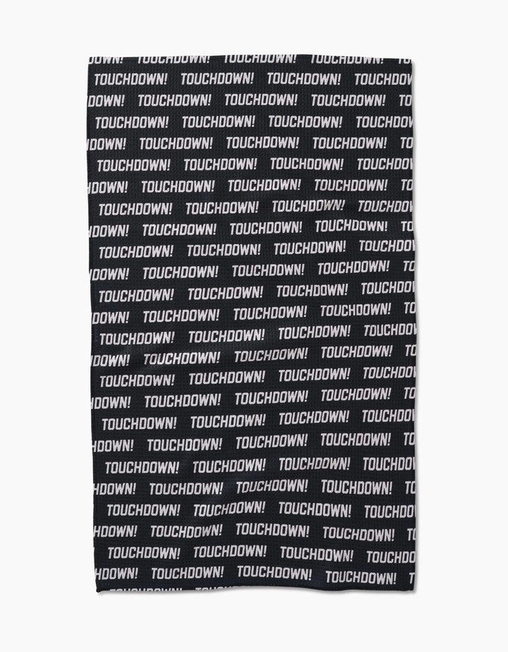The GEOMETRY Touchdown tea towel is made from recycled materials and features TOUCHDOWN! in bold white uppercase letters, printed repeatedly across its black Geoweave fabric in a striking horizontal pattern.