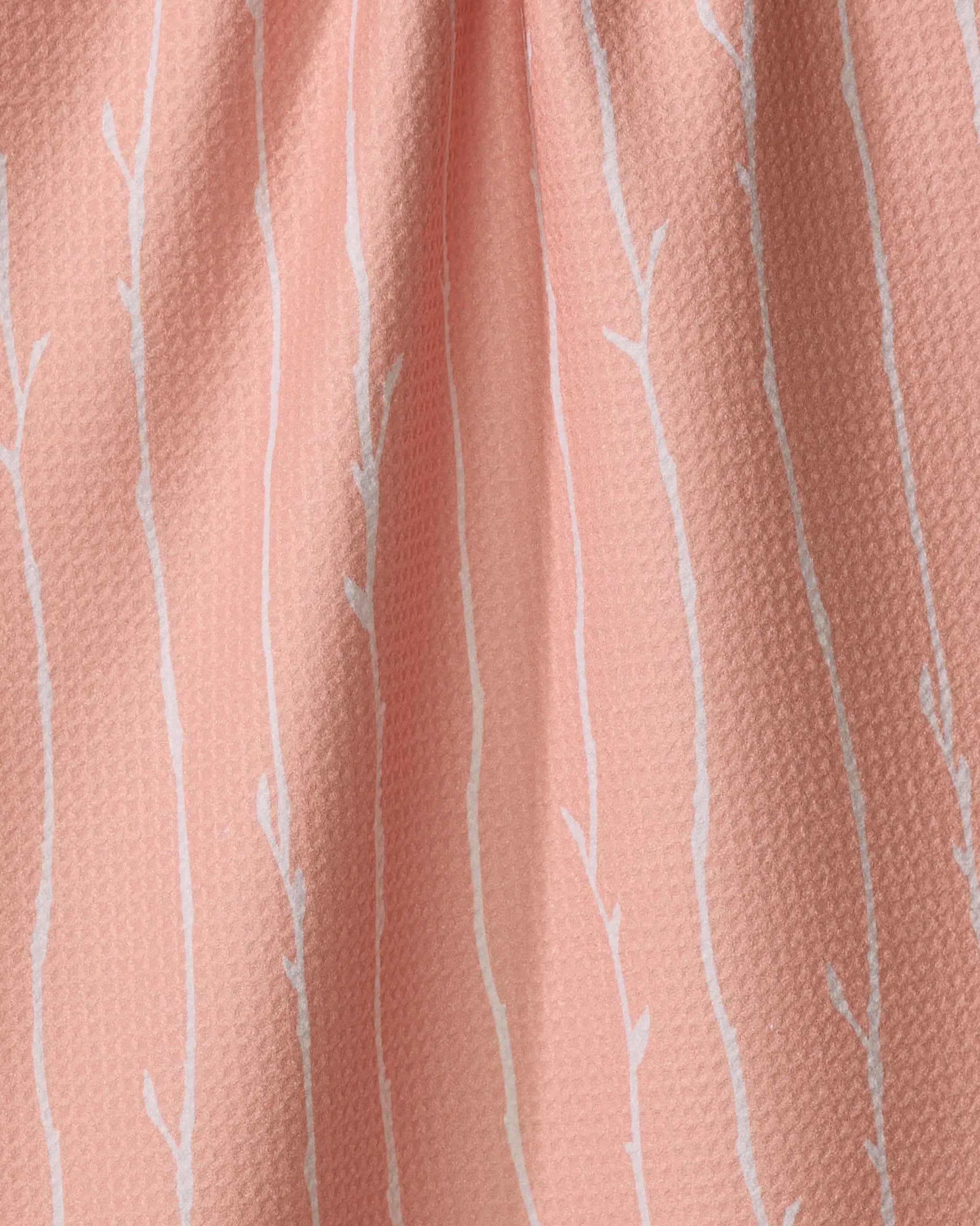 A close-up of the Towering Twigs tea towel by Twig + Spark, featuring light pink fabric with thin white branch-like stripes, softly gathered folds, subtle texture, and made from recycled materials.