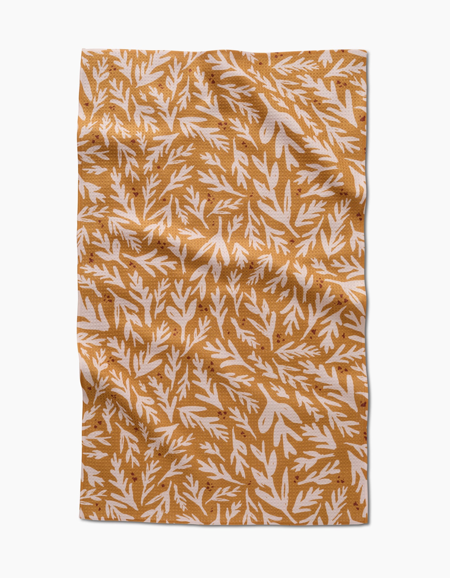 The Trail Dusting Gold napkin by Twig + Spark features a rectangular, wrinkled design with a mustard yellow background and white leafy branches, crafted from recycled materials for an eco-friendly touch.