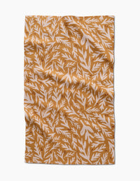 The Trail Dusting Gold napkin by Twig + Spark features a rectangular, wrinkled design with a mustard yellow background and white leafy branches, crafted from recycled materials for an eco-friendly touch.