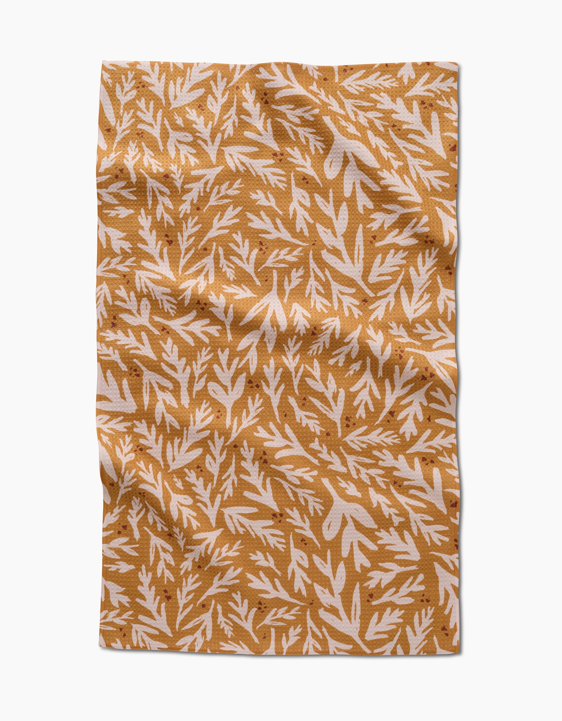 The Trail Dusting Gold napkin by Twig + Spark features a rectangular, wrinkled design with a mustard yellow background and white leafy branches, crafted from recycled materials for an eco-friendly touch.