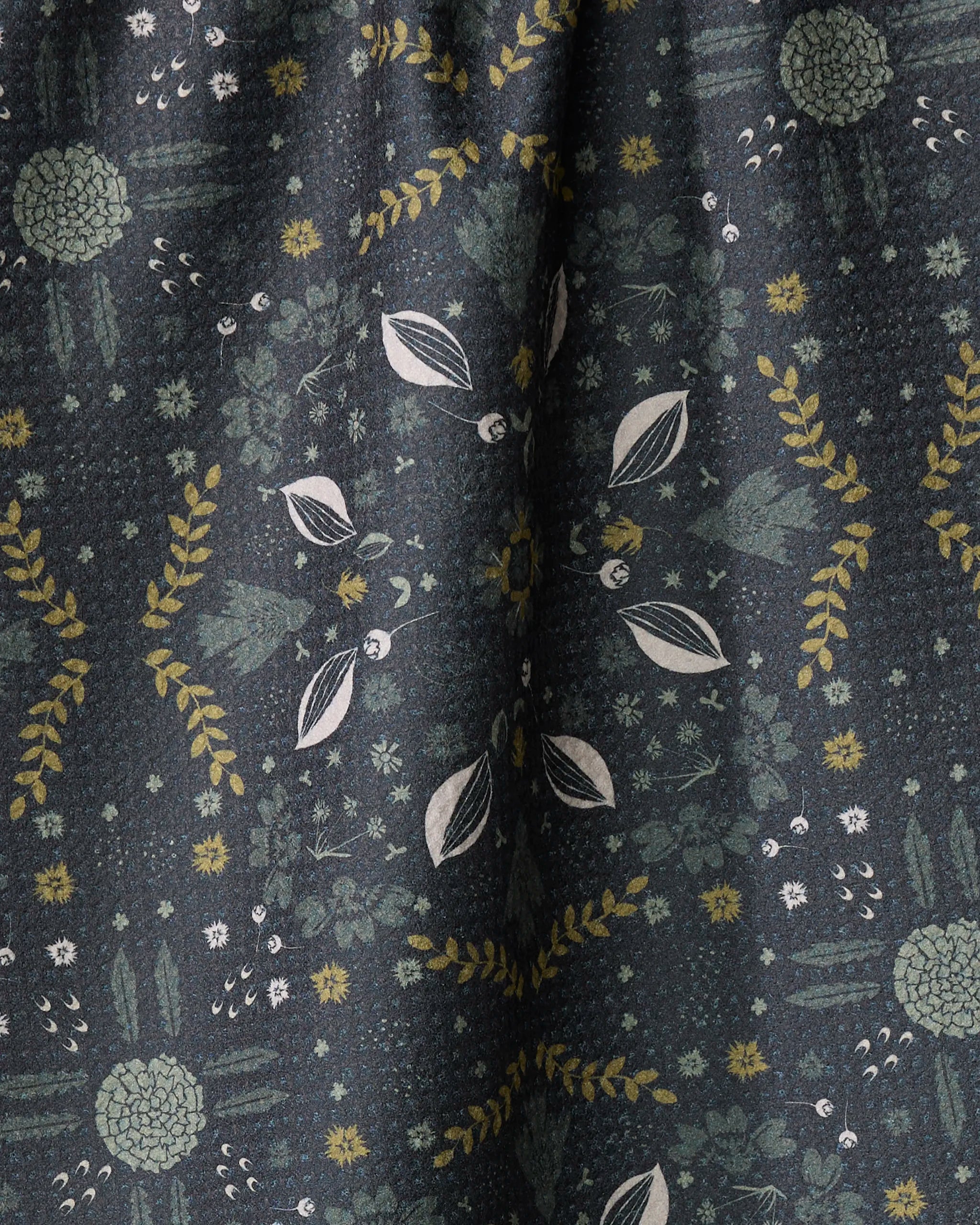 The Ash Cascade Trailhead towel features ultra-absorbent dark fabric adorned with green, yellow, and white botanical patterns in symmetrical, finely detailed arrangements for a natural, intricate look and soft drape.