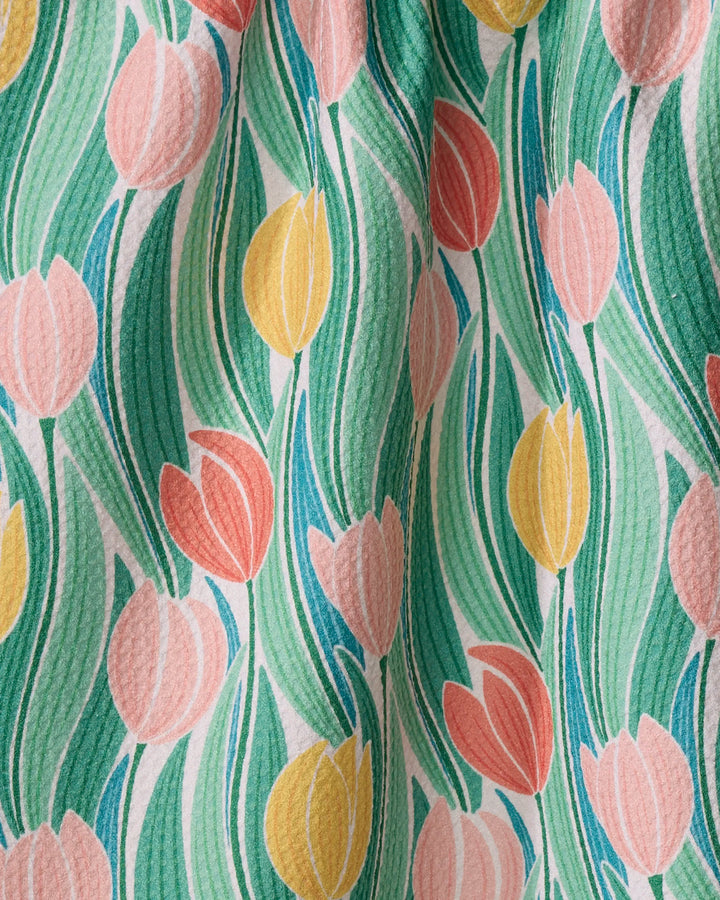 Add a charming, retro touch to your kitchen with the "Tranquil Tulips" towel by Sarah Daugherty, featuring pink, yellow, and red tulips with green leaves on textured fabric made from recycled materials.