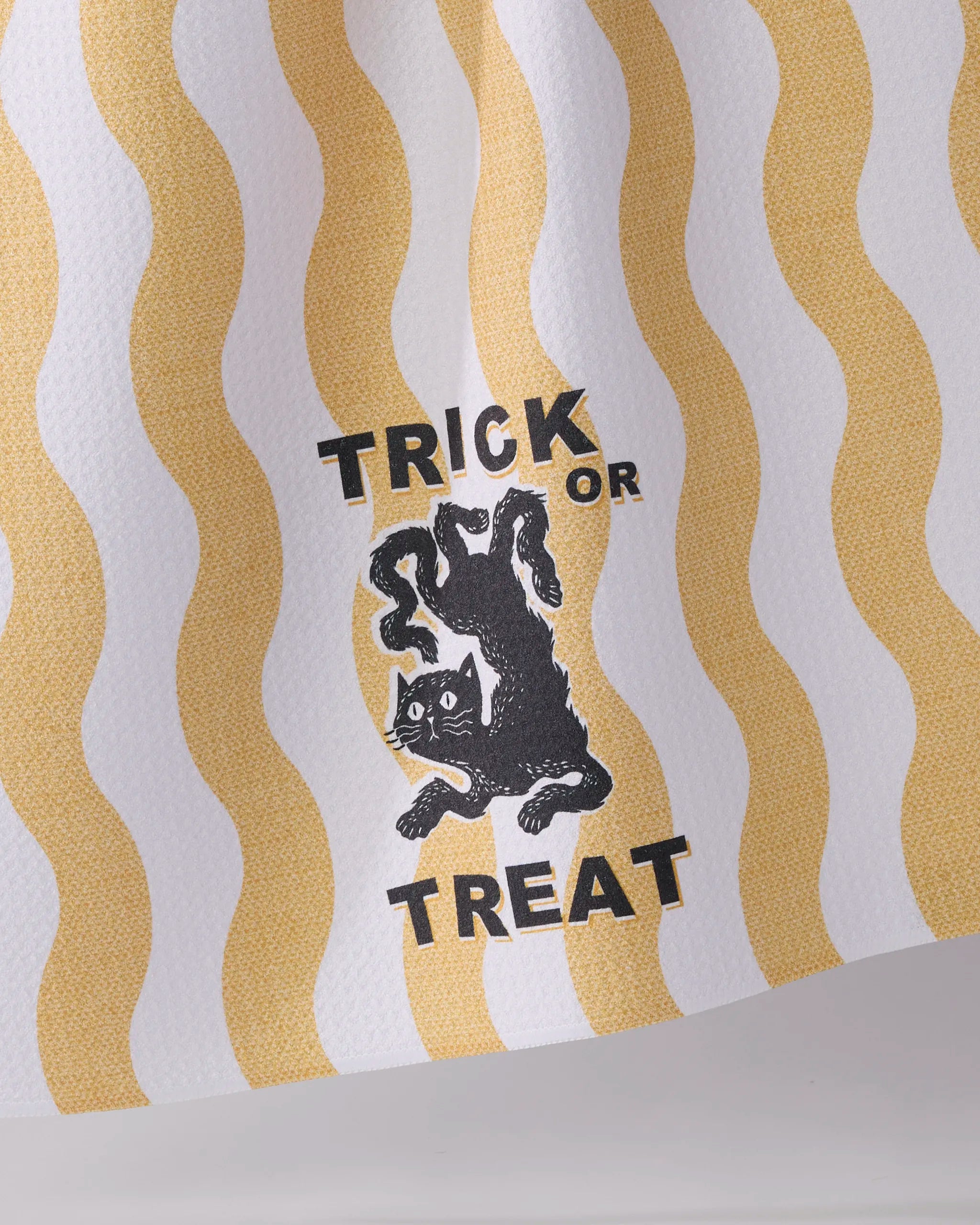 The Geometry "Treat Street" tea towel is ultra-absorbent, with wavy yellow stripes, a vintage black cat illustration, and bold "Trick or Treat" lettering.
