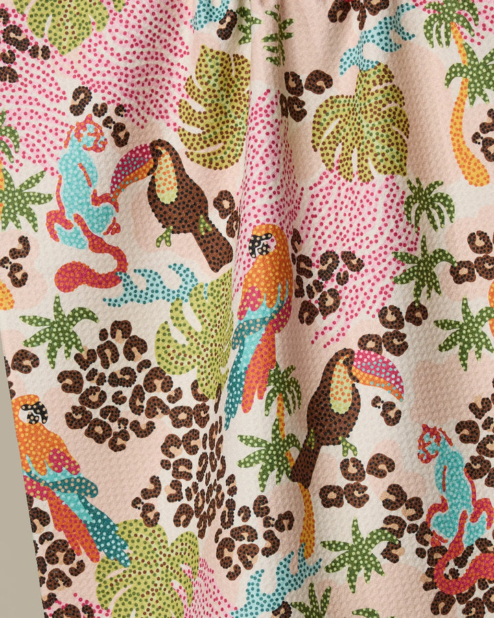 The Geometry Tropi Hotel is a colorful recycled kitchen towel with a dotted pattern of parrots, toucans, monkeys, green tropical leaves, and brown animal prints on a light background.