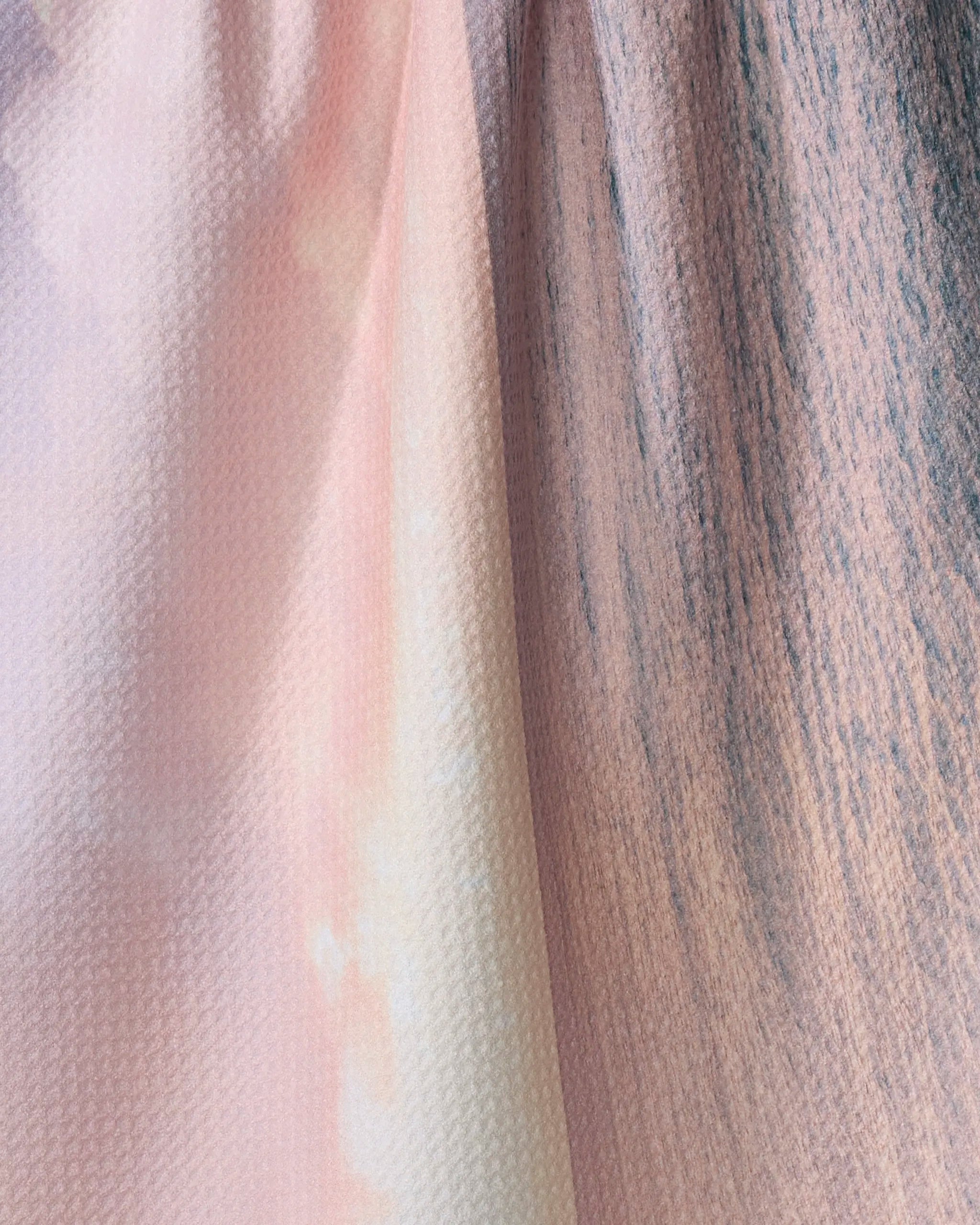 Close-up of Kait Hanson's Tropical Sunrise tea towel, featuring an absorbent, subtly textured weave and a soft pastel gradient blending pink, peach, and light gray tones.