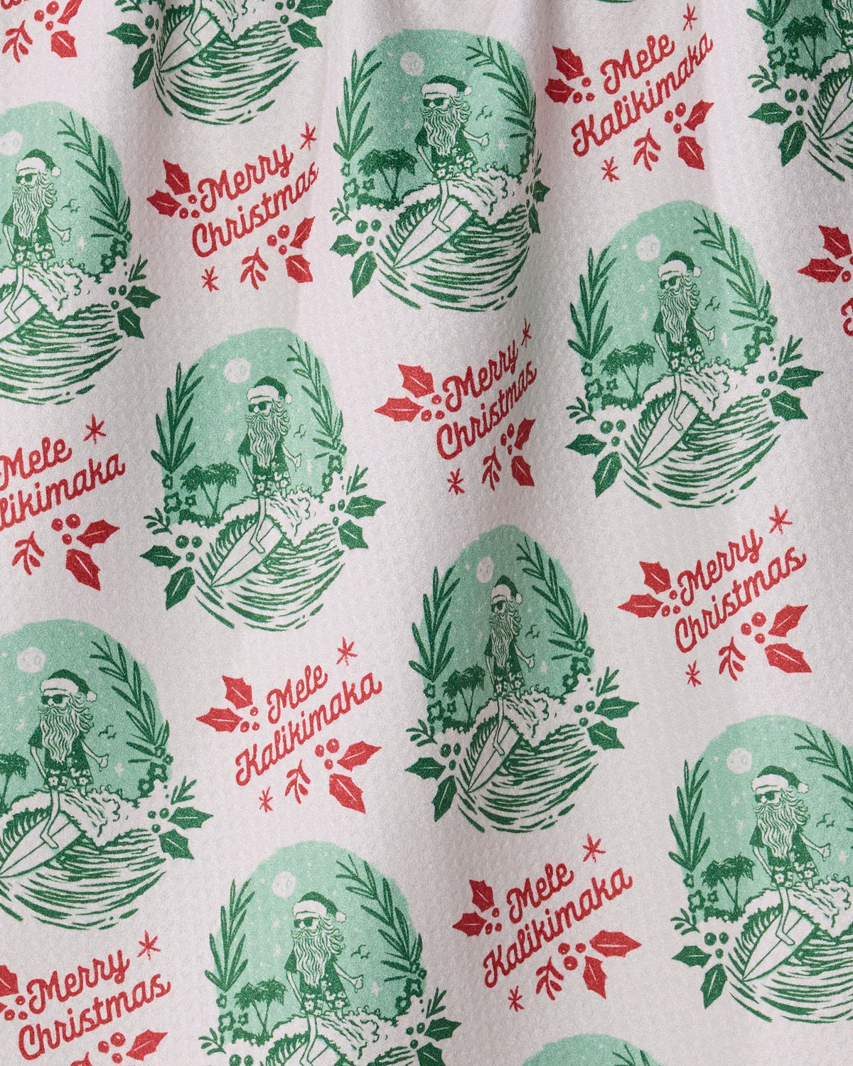 Geometry’s Tropical Tidings festive wrapping paper features repeating patterns of a hula dancer, lush green leaves, red “Merry Christmas” and “Mele Kalikimaka” text, and vibrant red poinsettia flowers—perfect for pairing with a recycled kitchen towel as a thoughtful holiday gift.
