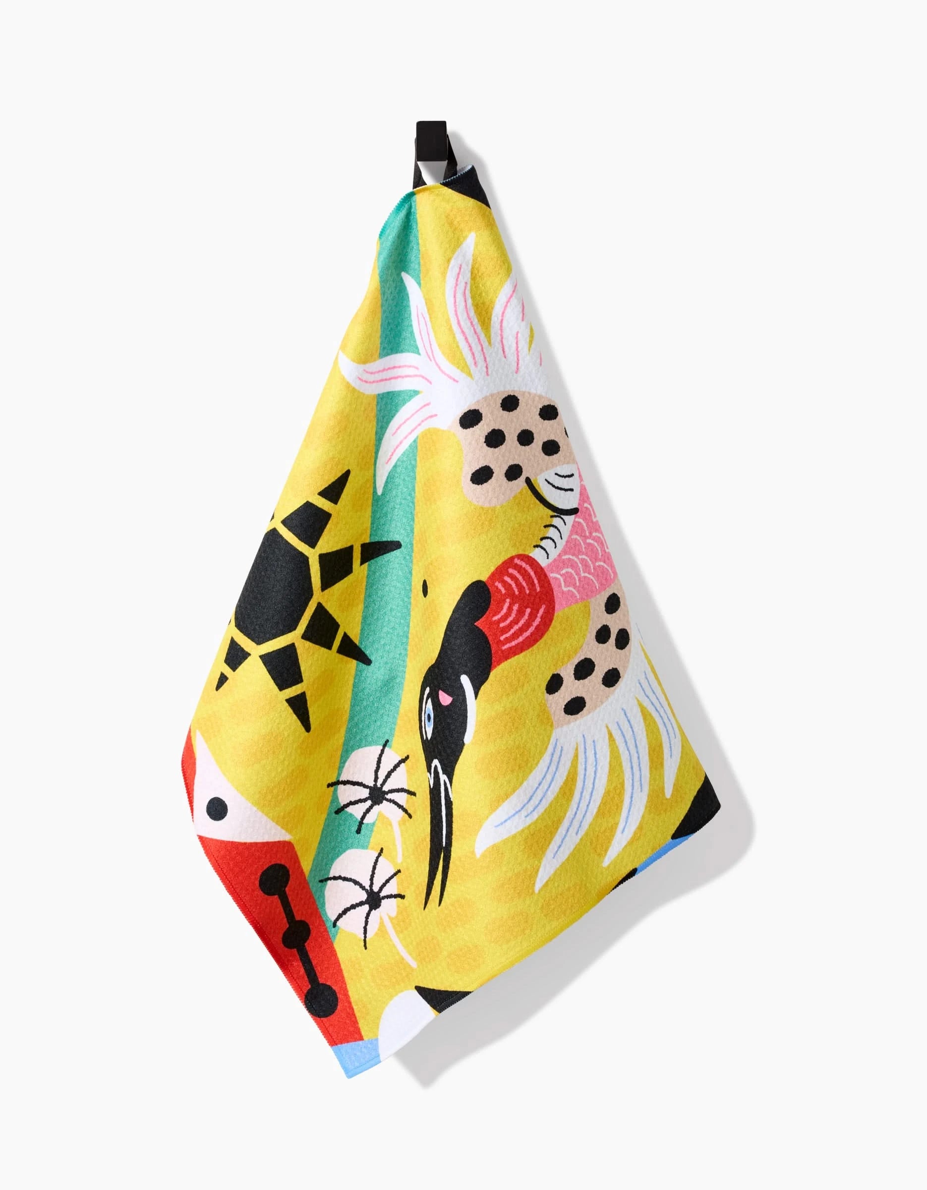 The Tuiuiú Tea Towel by Camila Leão features a stylized white crane with pink wings, a yellow sun, and bold abstract patterns on bright Geoweave fabric, and hangs by a black loop.