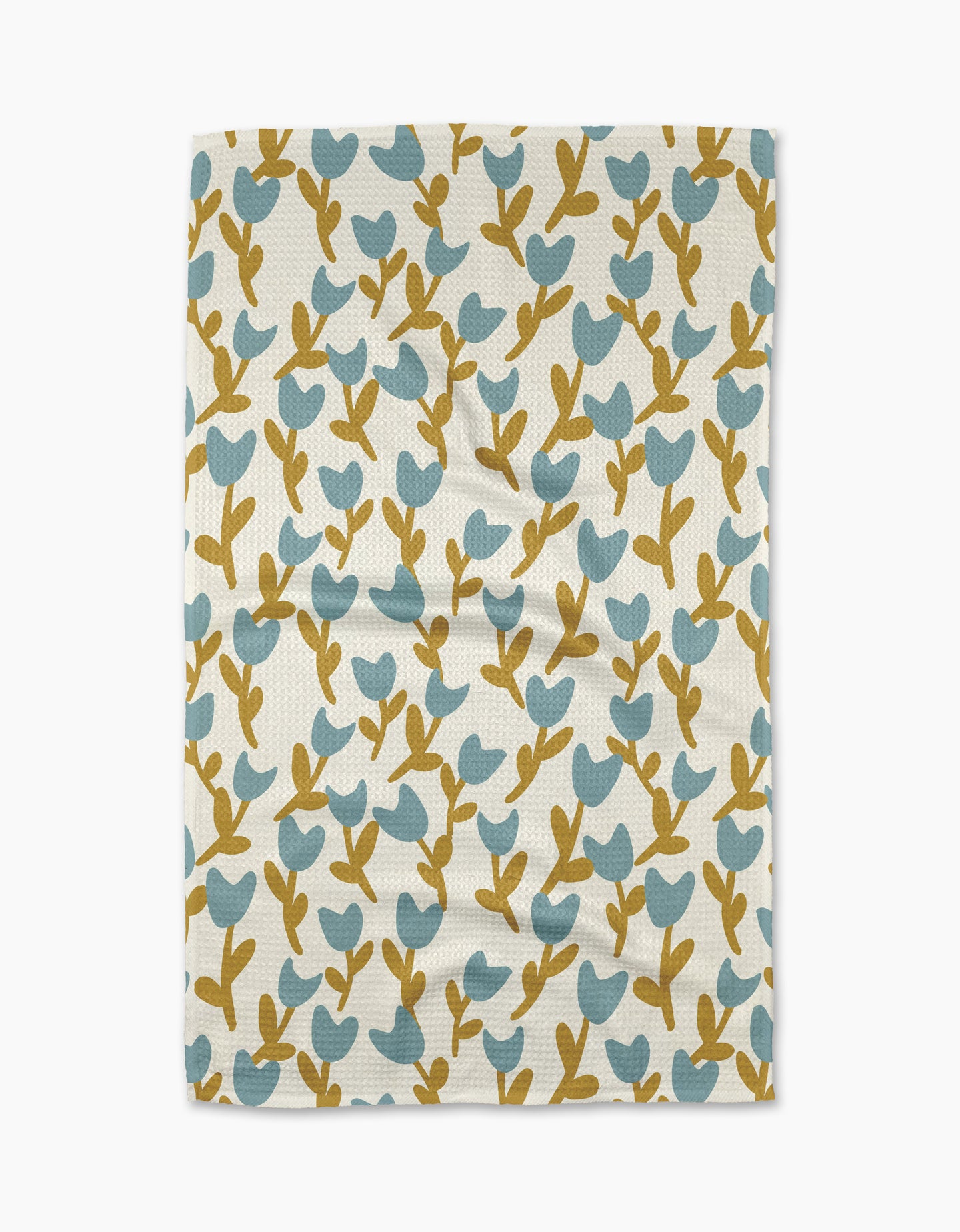 The Tulip Garden tea towel by Lizzie Clark is a rectangular, white towel made from recycled materials, featuring blue and mustard yellow stylized leaf and branch patterns. Displayed flat with slight wrinkles.
