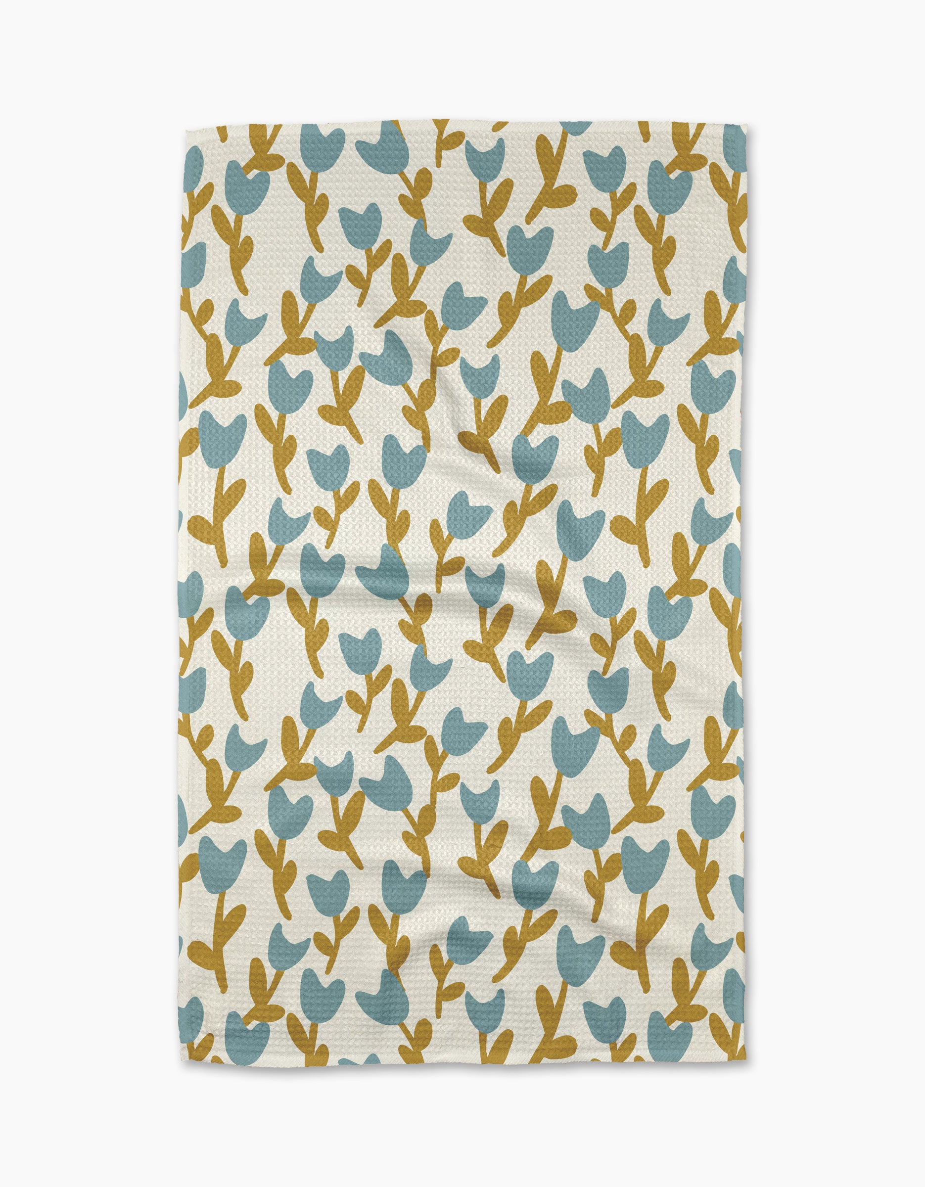 The Tulip Garden tea towel by Lizzie Clark is a rectangular, white towel made from recycled materials, featuring blue and mustard yellow stylized leaf and branch patterns. Displayed flat with slight wrinkles.