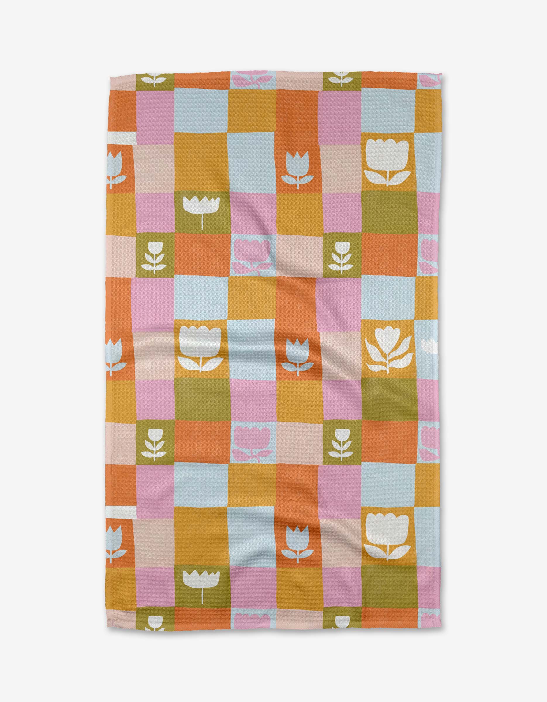 The Tulip Picnic tea towel by Lisa Nelson features a checkered pattern in pastel blue, pink, orange, yellow, and green with white or pink floral and tulip designs. Made from recycled materials, it is shown laid flat on a white background.