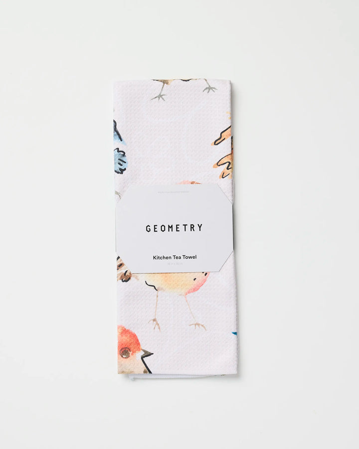 A white, absorbent kitchen towel featuring watercolor bird illustrations, called "Tweet Tweet" by Sara Mari, is neatly folded with its label shown against a plain white background.