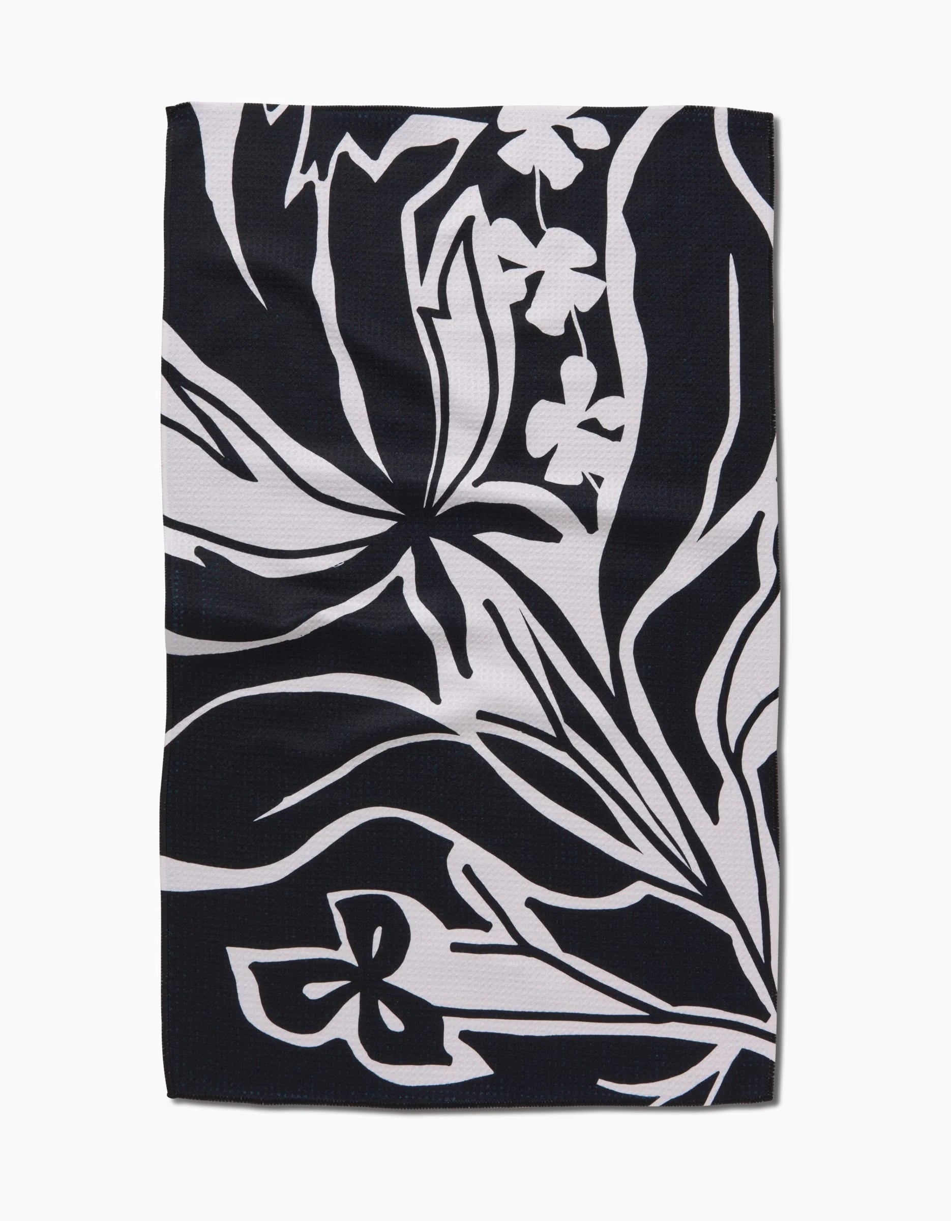 The Ash Cascade Twilight Plant is a rectangular black kitchen towel with abstract white floral and leaf patterns. Bold lines and stylized shapes create a modern, eco-friendly accent for any space.