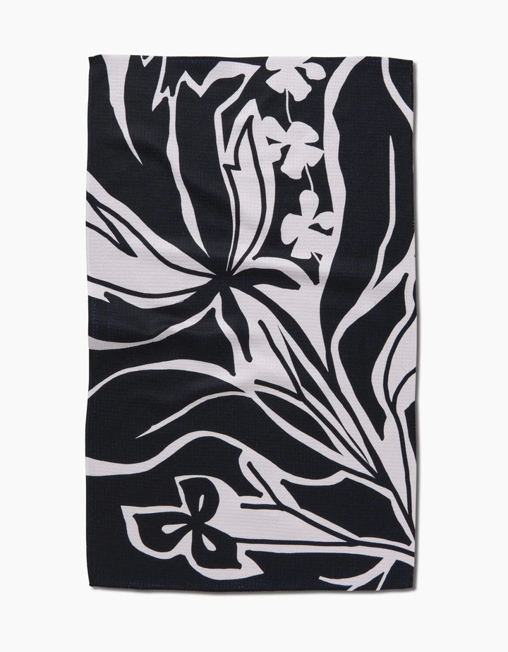 The Ash Cascade Twilight Plant is a rectangular black kitchen towel with abstract white floral and leaf patterns. Bold lines and stylized shapes create a modern, eco-friendly accent for any space.