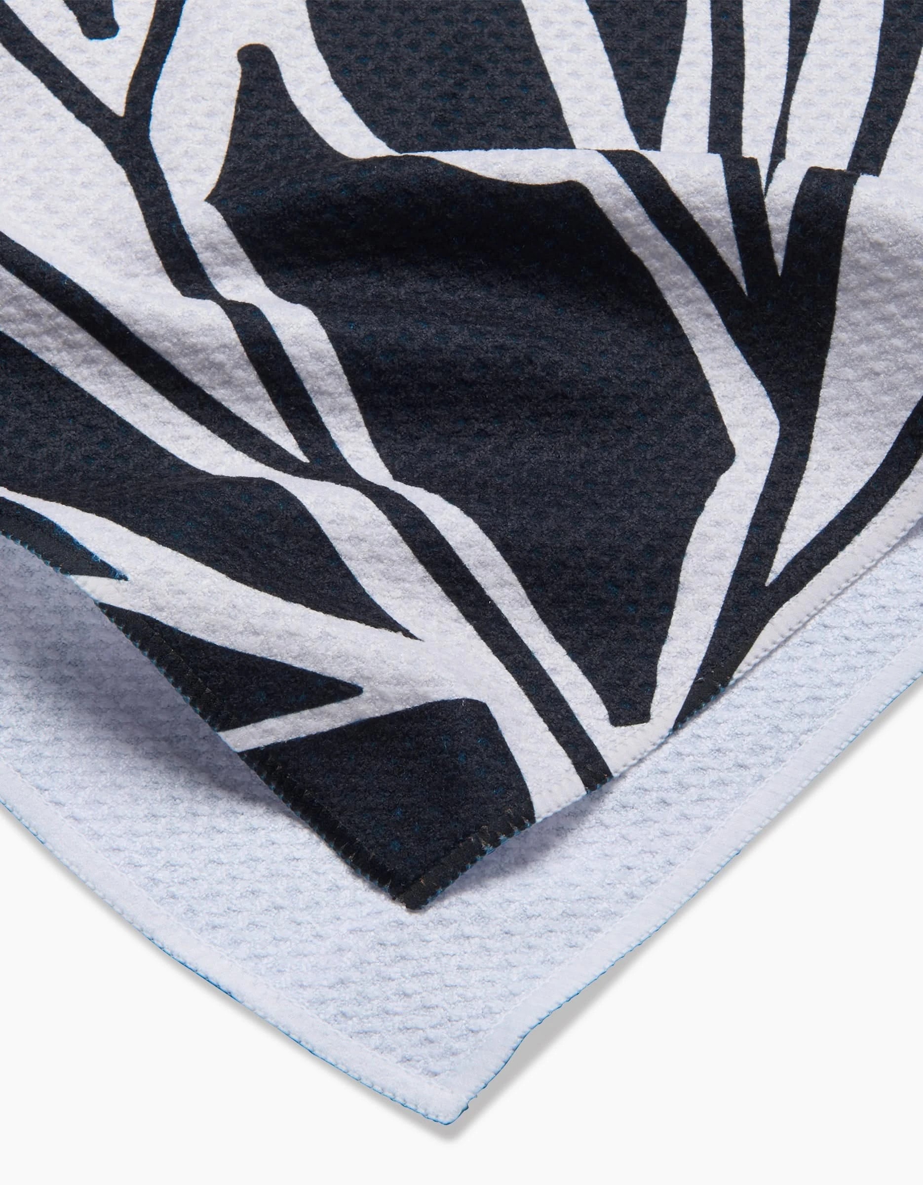 Close-up of Ash Cascades Twilight Plant kitchen towel, featuring a black and white abstract botanical pattern on eco-friendly, textured fabric with neatly stitched edges.