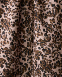 A close-up of Geometrys Umber dish towel, featuring an absorbent fabric with a leopard print in brown, black, and beige. Dark, irregular spots stand out on a light background with visible folds and textured detail.