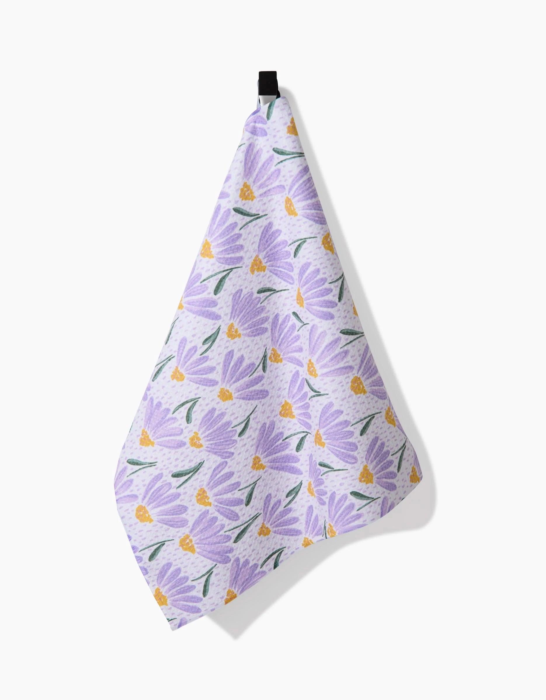 The Upside Down Daisy tea towel by Hufton Studio features soft Geoweave fabric with light purple flowers and green leaves on white, elegantly displayed against a plain background.