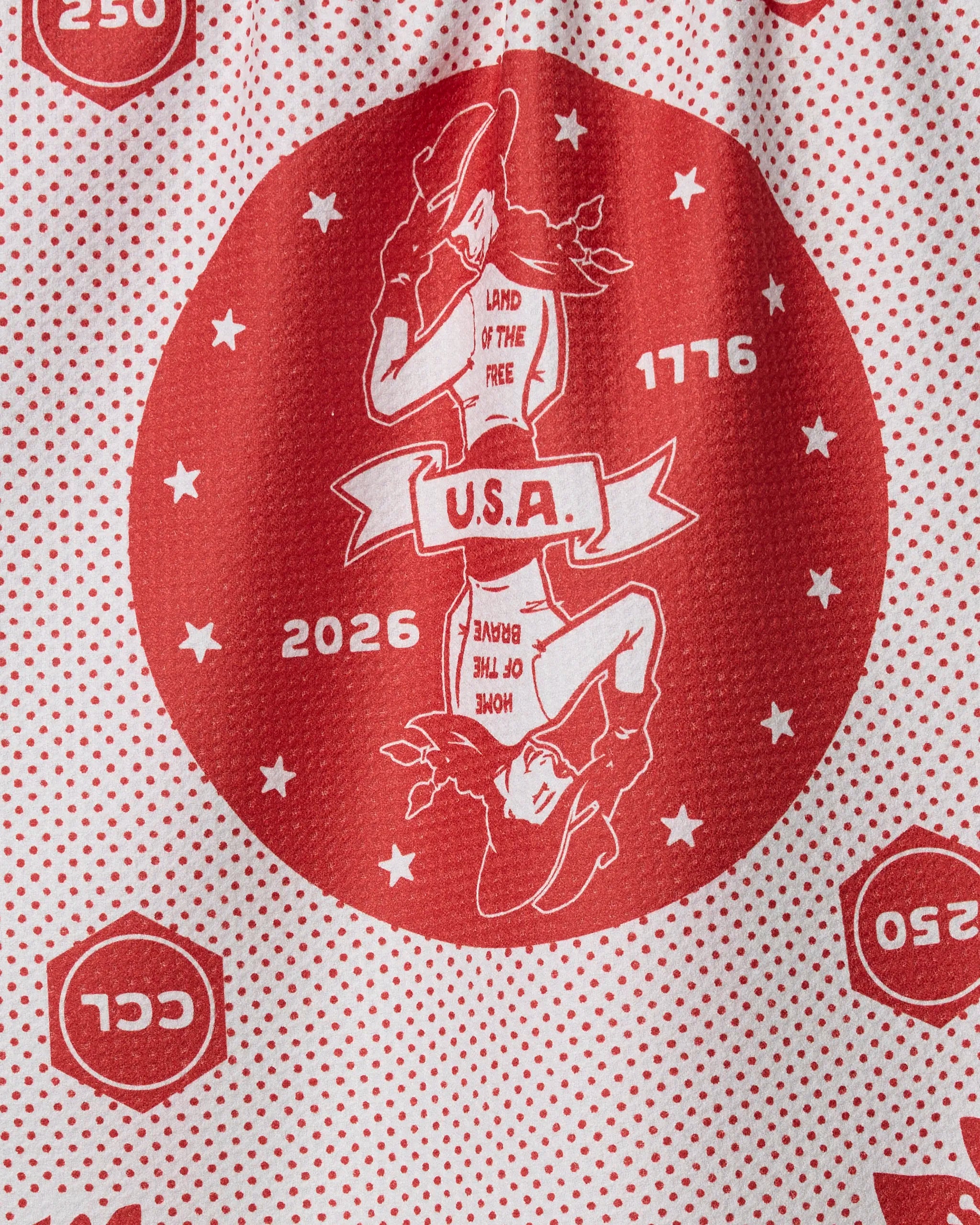 The Geometry USA Cowgirl tea towel features a red and white pattern, recycled materials, a cowgirl in a central circle, U.S.A. banner, stars, 1776 & 2026 dates, plus “Land of the Free” and “Home of the Brave.”.