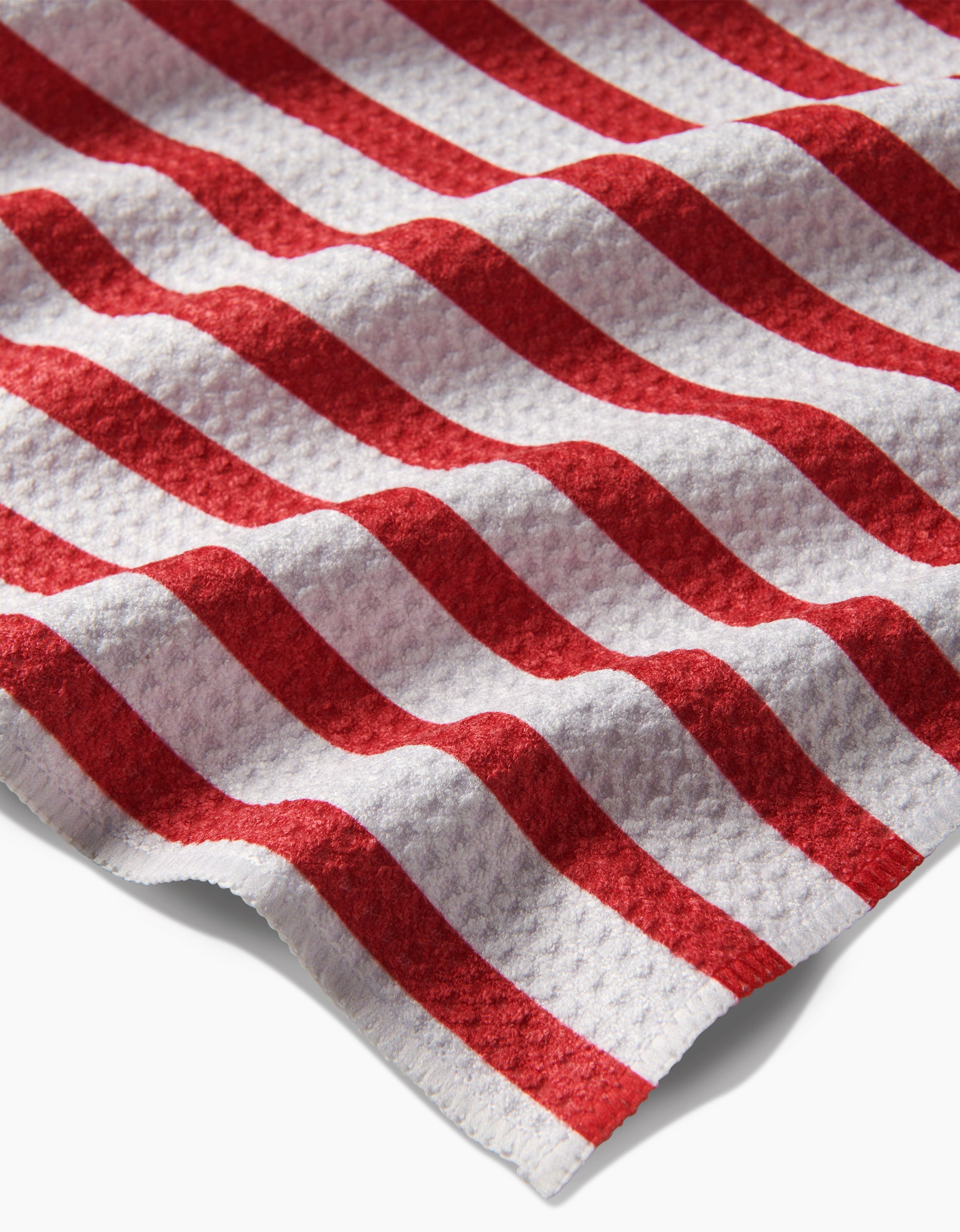 A close-up of the USA Stripes tea towel by Mindfulnice reveals diagonal red and white stripes on textured Geoweave fabric, designed for superior absorbency.