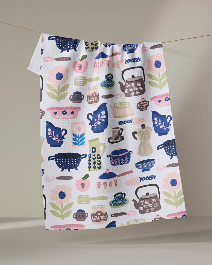 The "Utensils" tea towel by Cottonflower Studio is made from recycled materials and features colorful kitchen items in blue, pink, green, and brown on a neutral background. Ultra-absorbent and stylish—perfect for any kitchen.
