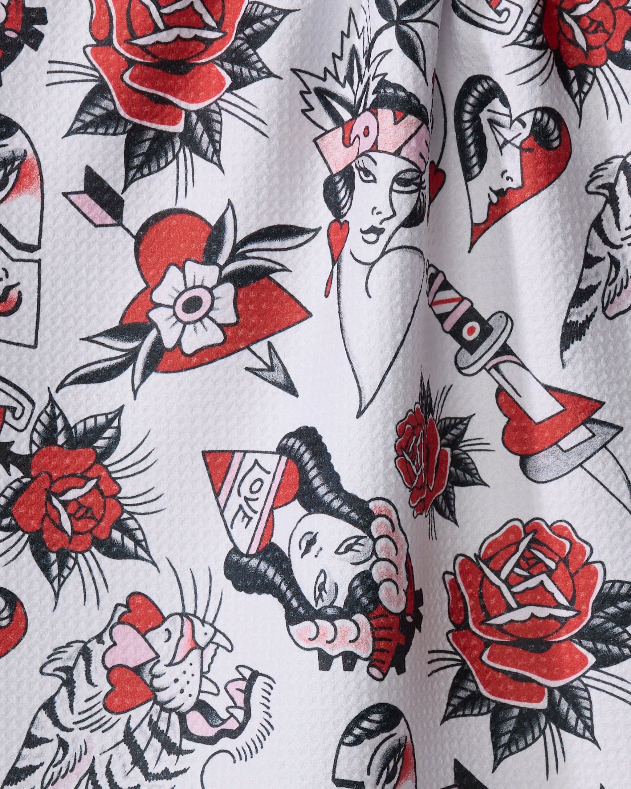 “Valentine’s Flash” by Cole Strem features tattoo-style red and black roses, hearts, daggers, tigers, and vintage women on white—a quick-drying tea towel made from recycled materials.