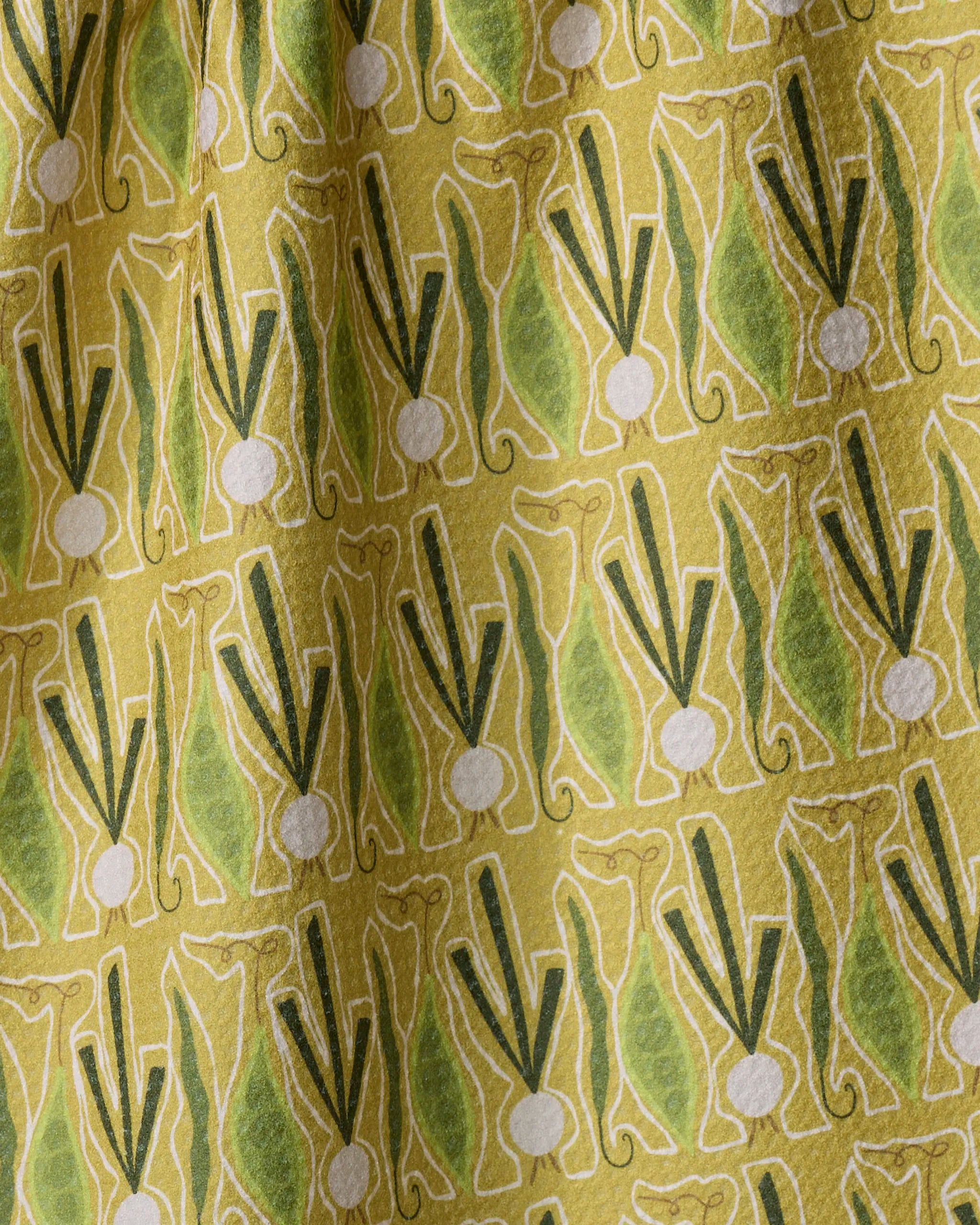The Veg on Parade dish towel by Lizzie Clark features repeated green and yellow stylized leeks on a textured, slightly wrinkled yellow background.
