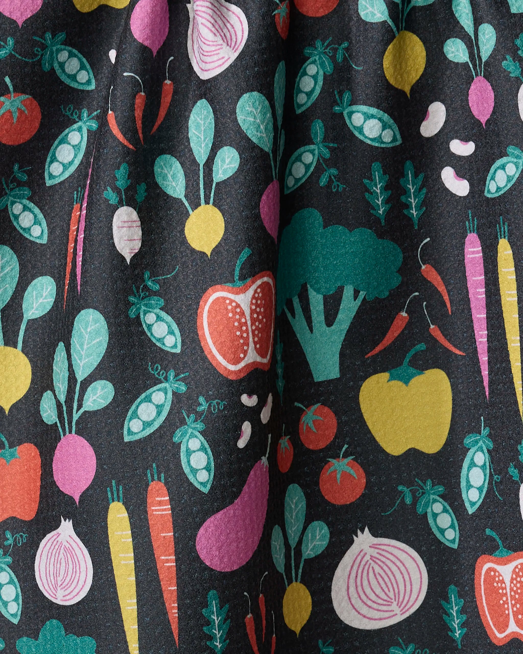 The “Veggies” tea towel by Megan Kampa features colorful illustrations of carrots, peppers, radishes, broccoli, and more on black fabric—an absorbent, eye-catching accent for any kitchen.