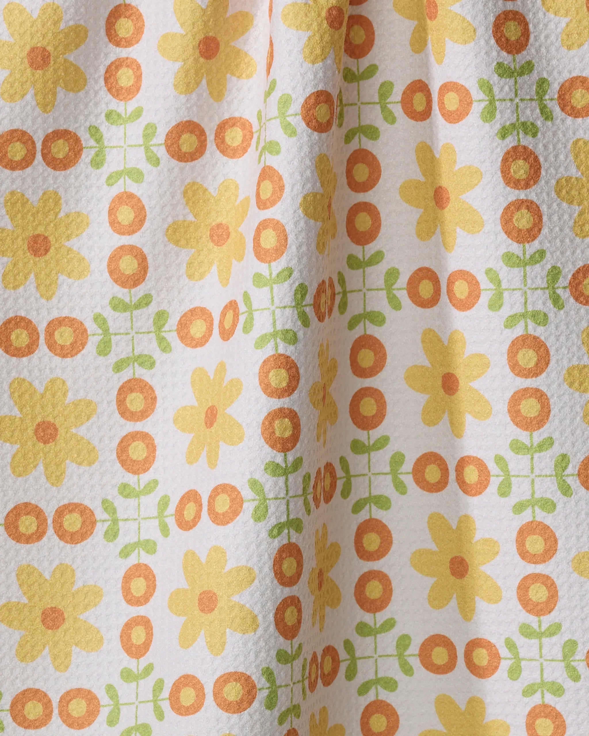 The Mindfulnice "Vintage Blooms" tea towel features yellow flowers, orange circles, and green leaves in a grid on white. Made from ultra-absorbent recycled materials, it’s an eco-friendly, stylish choice for your kitchen.