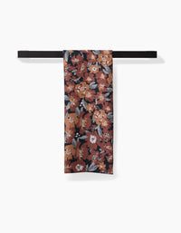 A Hufton Studio Vintage Floral Natural tea towel with a red, orange, white, and gray floral pattern hangs neatly over a black bar, featuring ultra-absorbent Geoweave fabric on a white background.