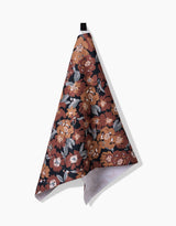 The Hufton Studio Vintage Floral Natural tea towel features a hanging black loop, an orange, brown, and white floral pattern on a dark background, and is made from ultra-absorbent Geoweave fabric for stylish functionality.