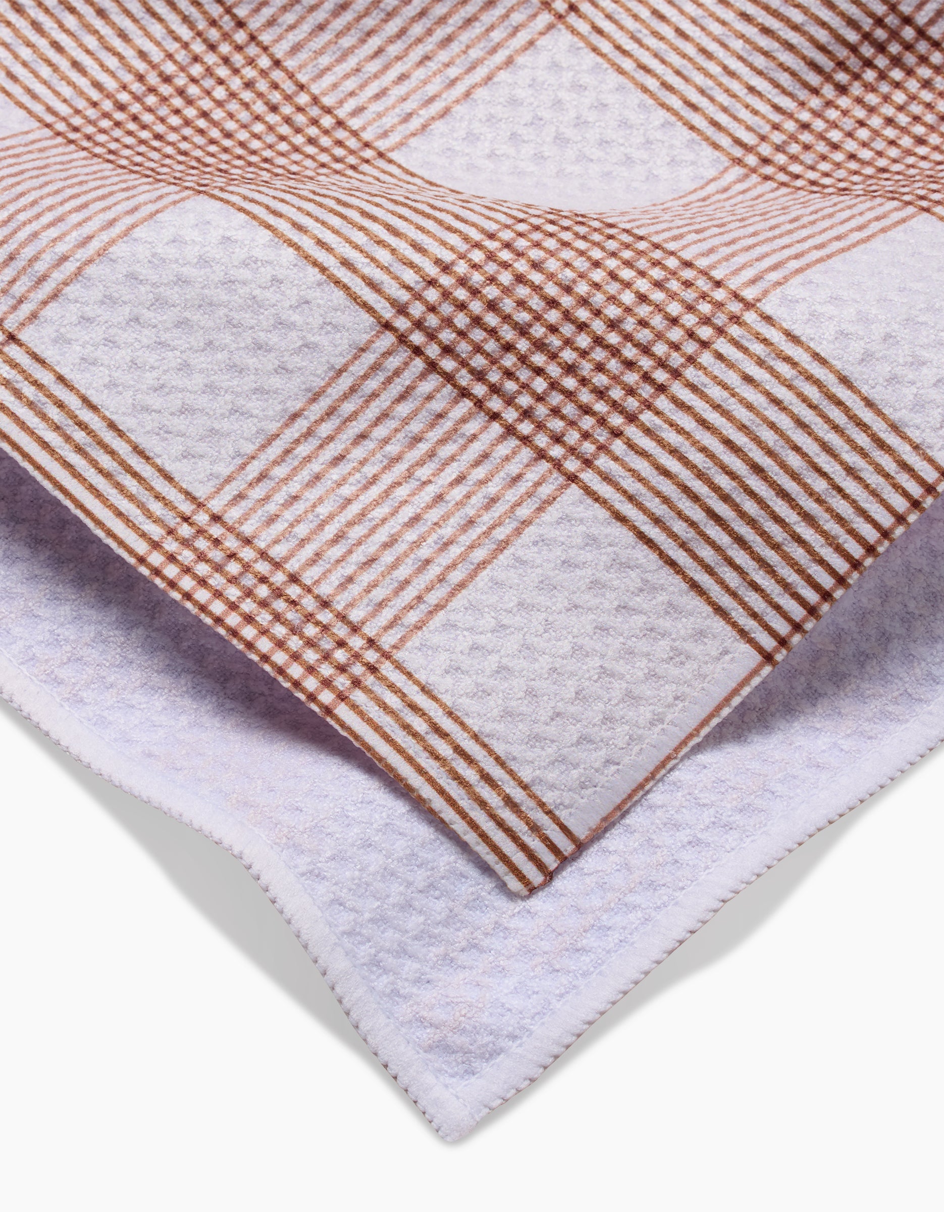 A close-up of Hufton Studios Vintage Gingham Natural tea towel, showing its brown and white checkered front, plain white Geoweave reverse, and neatly stitched edges.