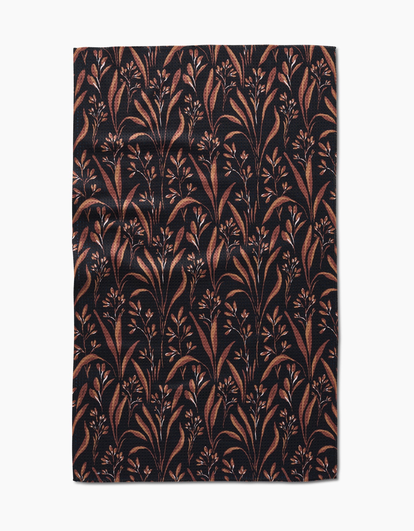 The Hufton Studio Vintage Grass Black tea towel is rectangular, made from Geoweave fabric, and features a black background with brown and tan leafy branches and small flowers, shown flat with slight wrinkles.