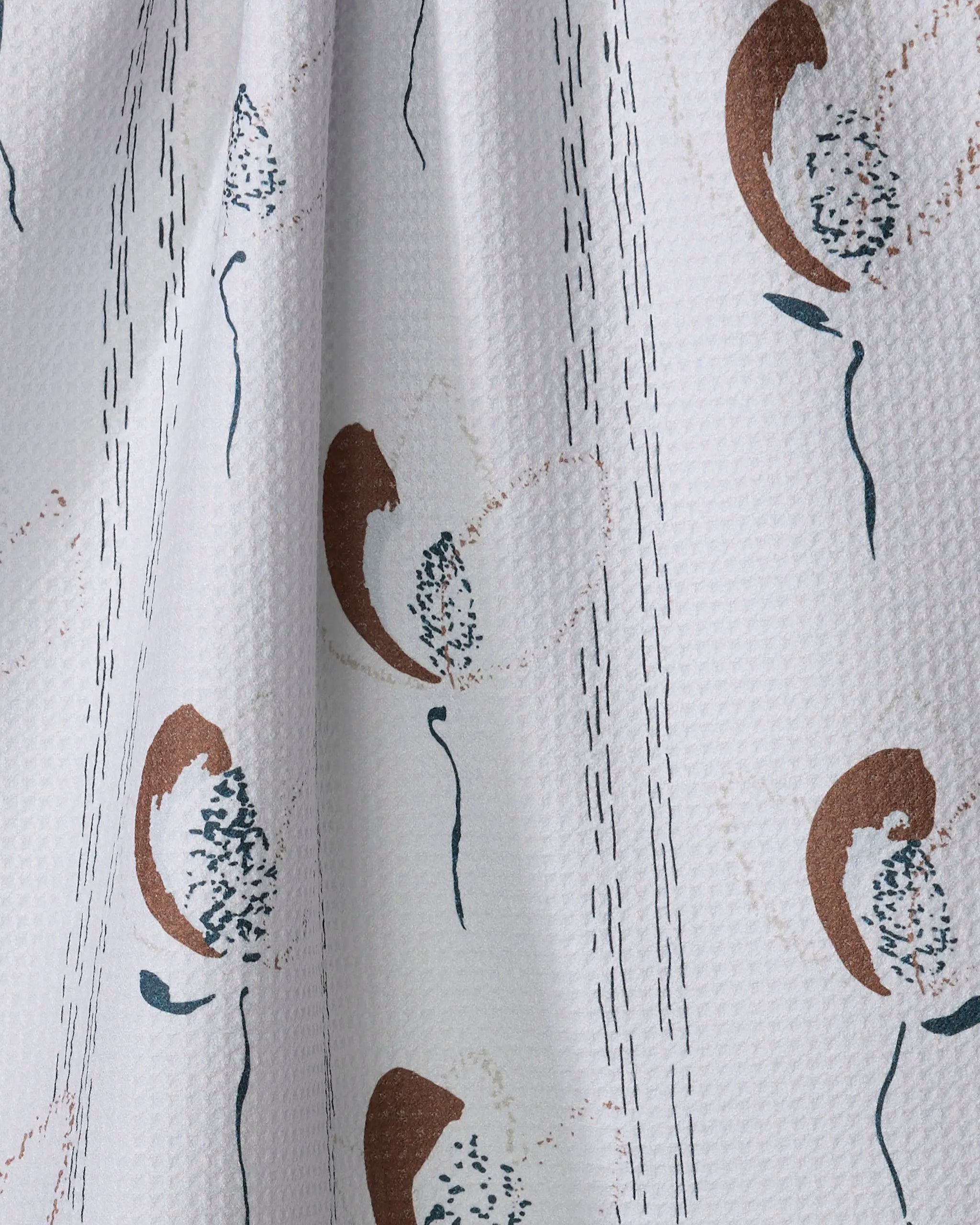 The "Vintage" kitchen towel by Toboggan Avenue features white textured recycled fabric with abstract brown, tan, and dark green floral designs and vertical dashed lines—offering style and absorbency for everyday use.