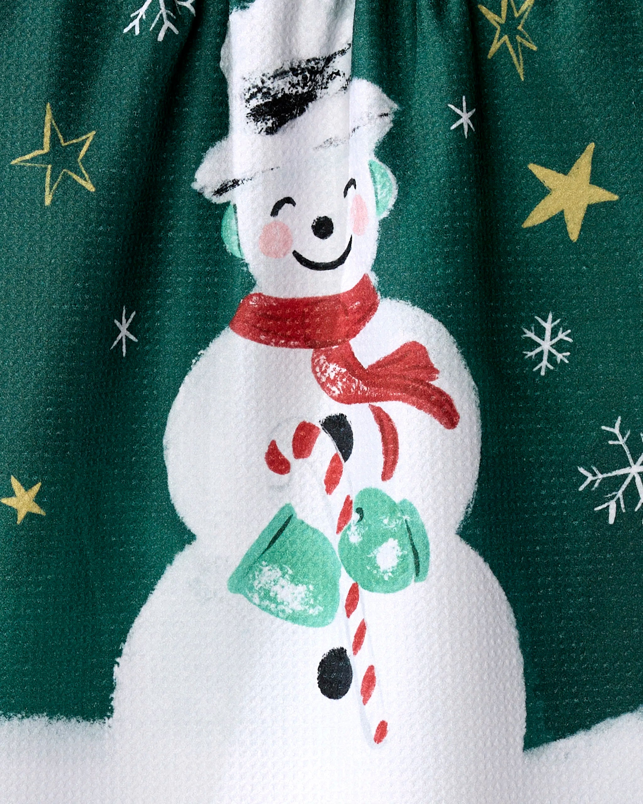 Cheerful Vintage Snowman by Louise Pretzel: wearing earmuffs, scarf, and hat, holding a candy cane and green mittens amid stars and snowflakes on green—perfect design for an absorbent kitchen or tea towel.