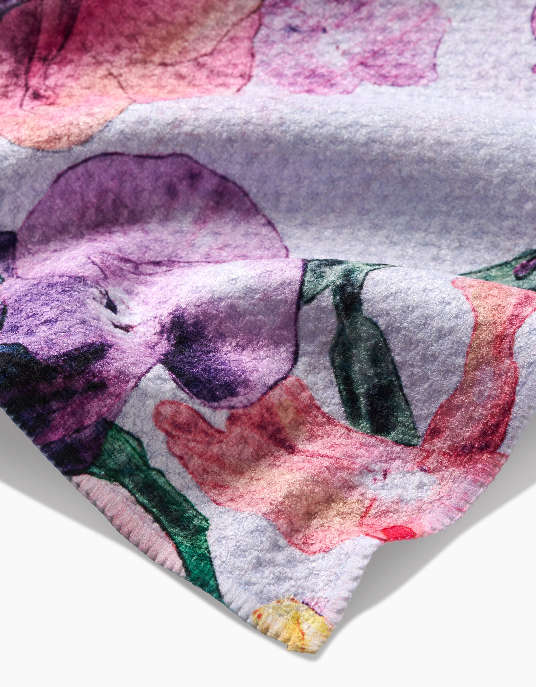 A close-up of Pascale Dilger’s Wallflower highlights its ultra-absorbent Geoweave fabric, featuring a soft watercolor floral print in purple, pink, green, and yellow on a light background.
