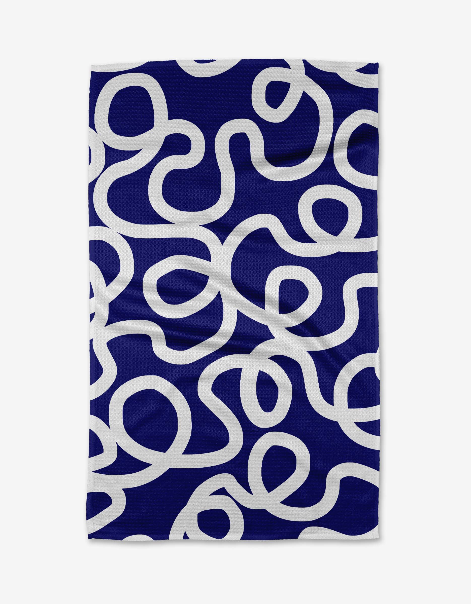 The Wander tea towel by Rachel Parker is blue and rectangular, featuring an abstract design with thick white winding lines curving and looping across its surface.
