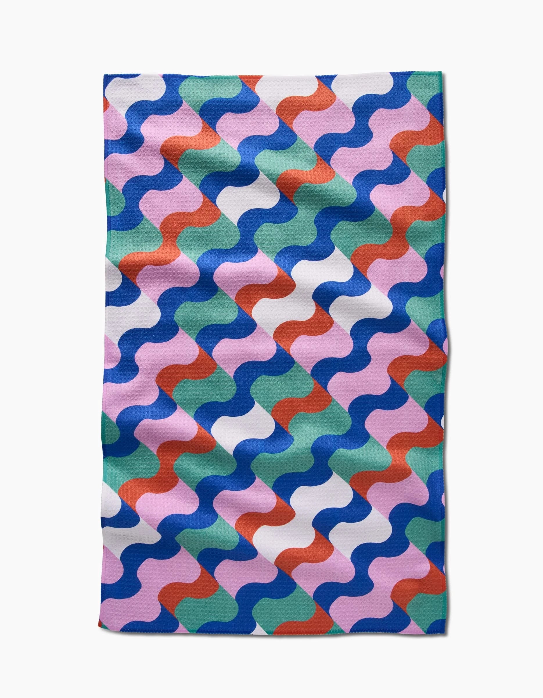 The Claire Iglesias Wavy Stripes Tea Towel features a wavy, interlocking blue, green, pink, red, and white pattern on Geoweave fabric. Its rectangular shape and subtly uneven edges highlight the towels texture and quality.