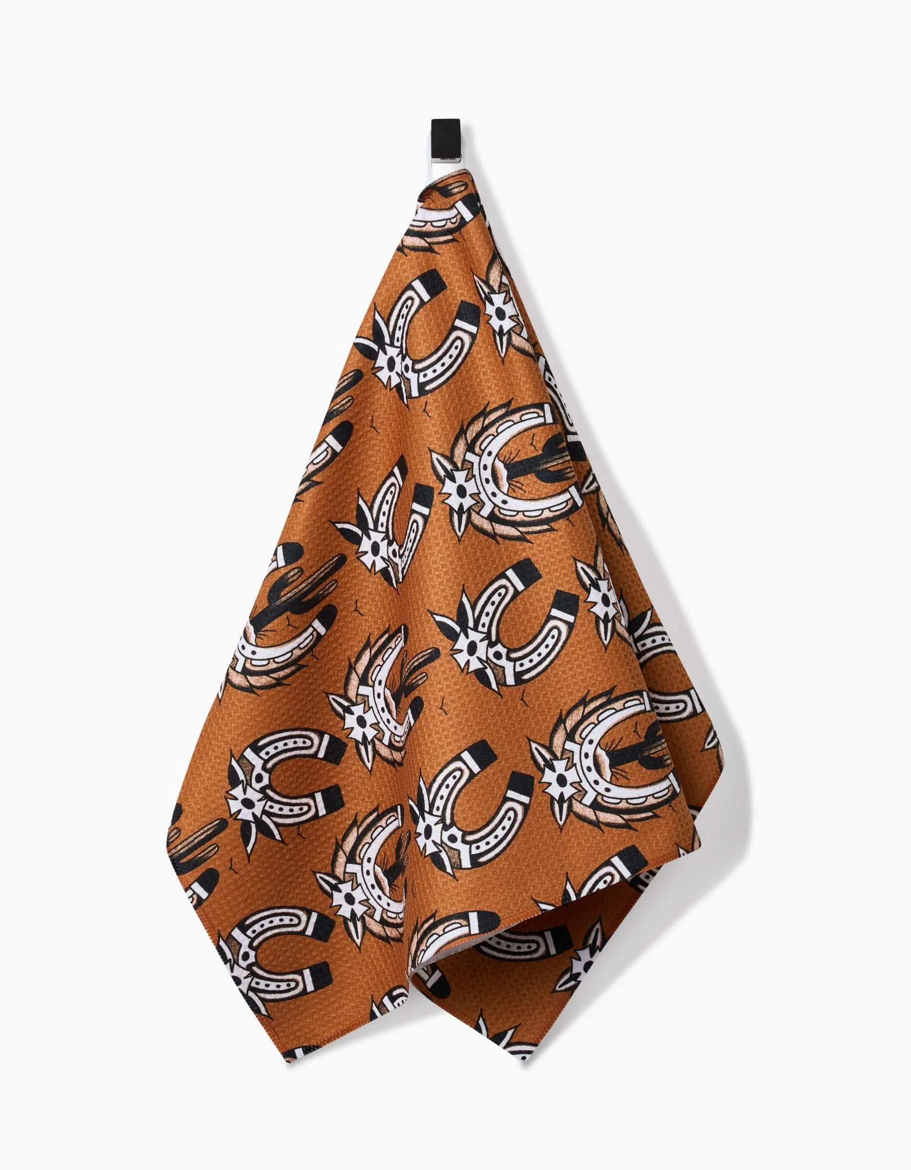 The Cole Strem Western Horseshoes tea towel, made from ultra-absorbent Geoweave fabric, features black and white horseshoes and starbursts on brown, hanging from a black loop against a white background.