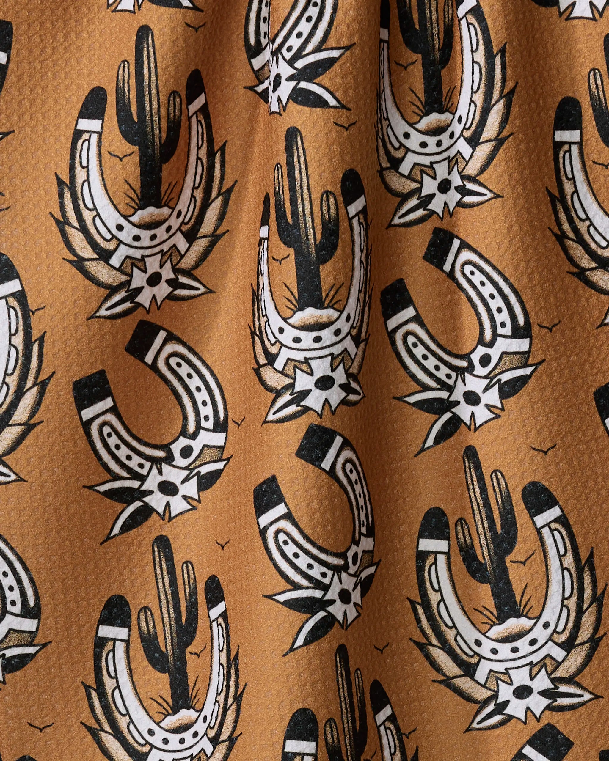 The Cole Strem "Western Horseshoes" tea towel features ultra-absorbent patterned fabric with black and white horseshoes, cacti, and stars on a brown background, evoking a Southwestern vibe.