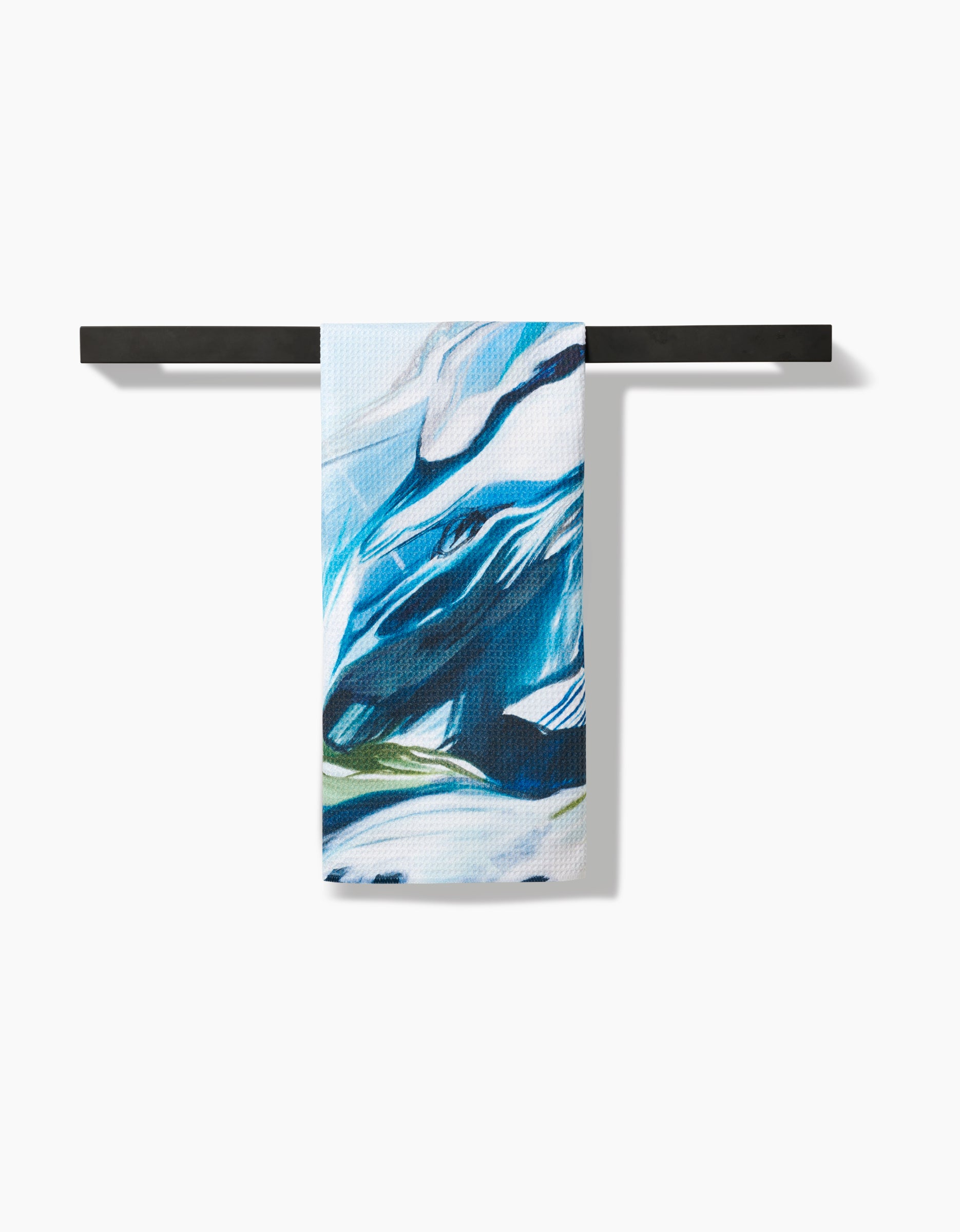 The Where He Laid To Go tea towel by Kelly Peters features blue, white, and black abstract patterns on durable Geoweave fabric, hanging neatly over a horizontal black bar against a white background.