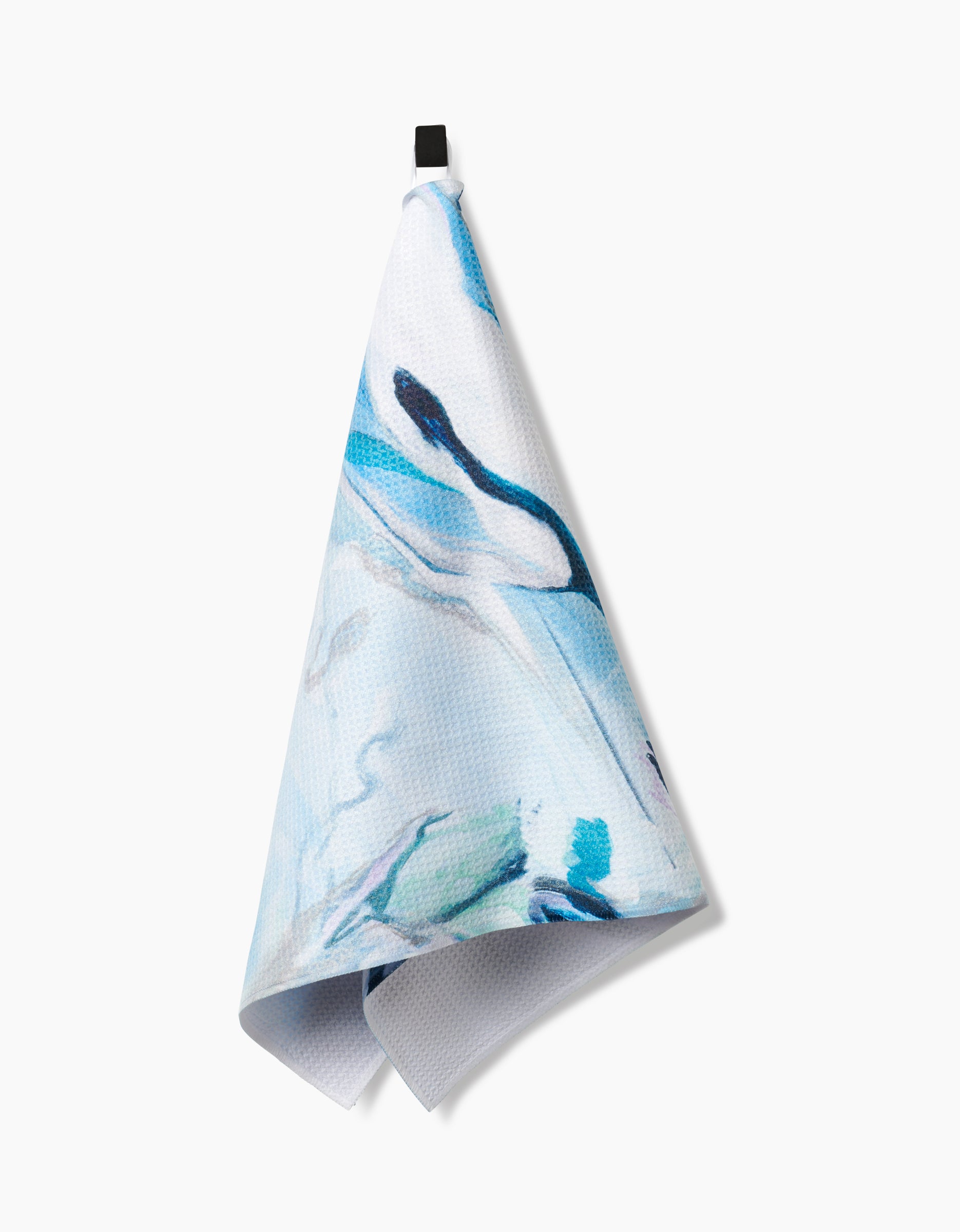 A blue and white patterned Kelly Peters Where He Laid To Go tea towel made from Geoweave fabric hangs from a black loop against a white background.