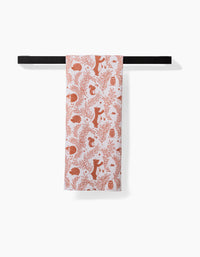 The Sara Mari Whimsical Woodland towel, featuring a red pattern of woodland animals and plants on white, hangs neatly on a black horizontal bar against a white background.