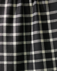 Close-up of Geometrys Wicklow Black: black fabric with a white plaid pattern, slightly gathered to form gentle vertical folds and subtle shadows across the grid design.
