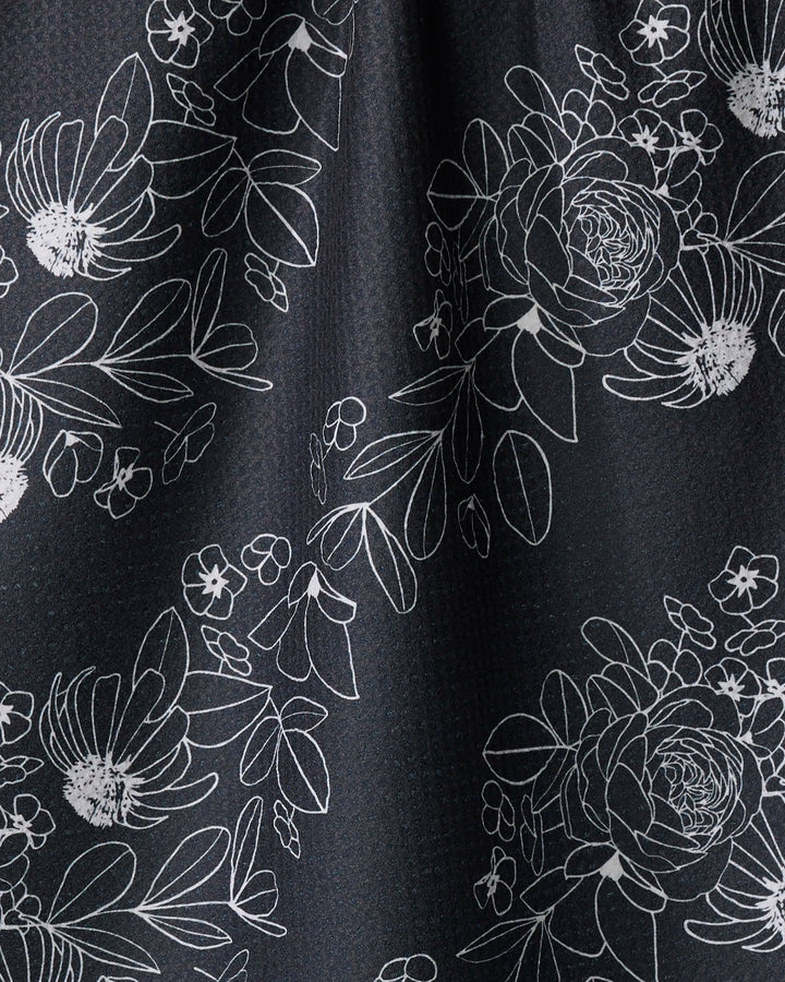 The "Wild and Wonderful" towel by Rosa Kichline features white floral and leaf outlines on a dark, textured background, offering an elegant, ultra-absorbent addition to your kitchen décor.