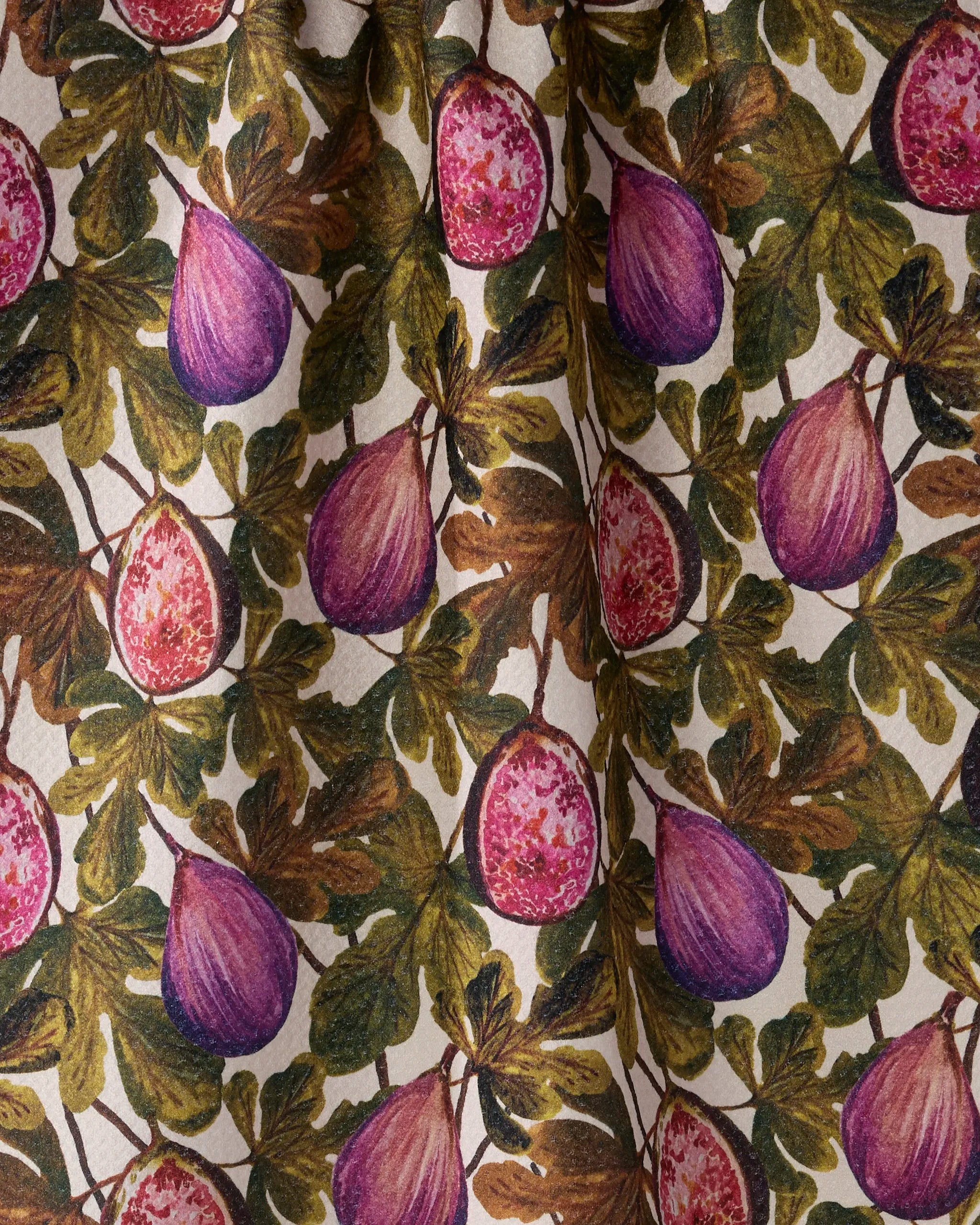 The Geometry Wild Fig tea towel features a repeating pattern of purple figs, some sliced open, with green and brown leaves on a cream background. Its gathered fabric adds soft folds and charm to your kitchen.