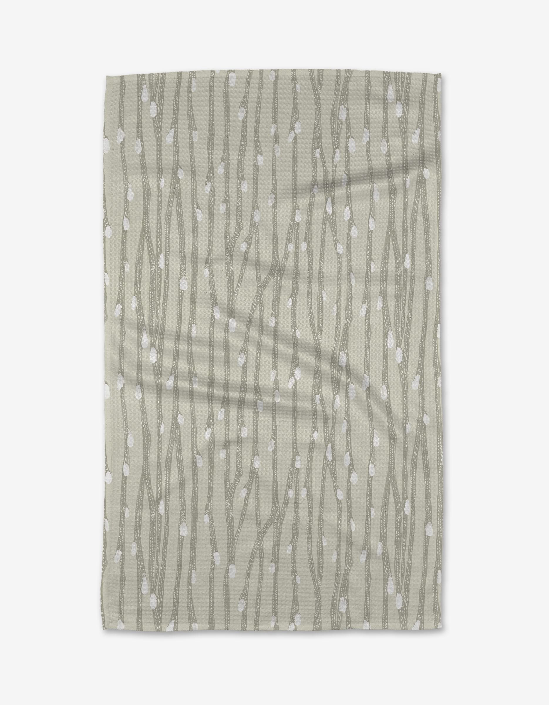 The Willow Branches tea towel by Katie OShea features a light gray background with vertical, wavy lines and scattered white dots, evoking the look of stylized branches or vines.