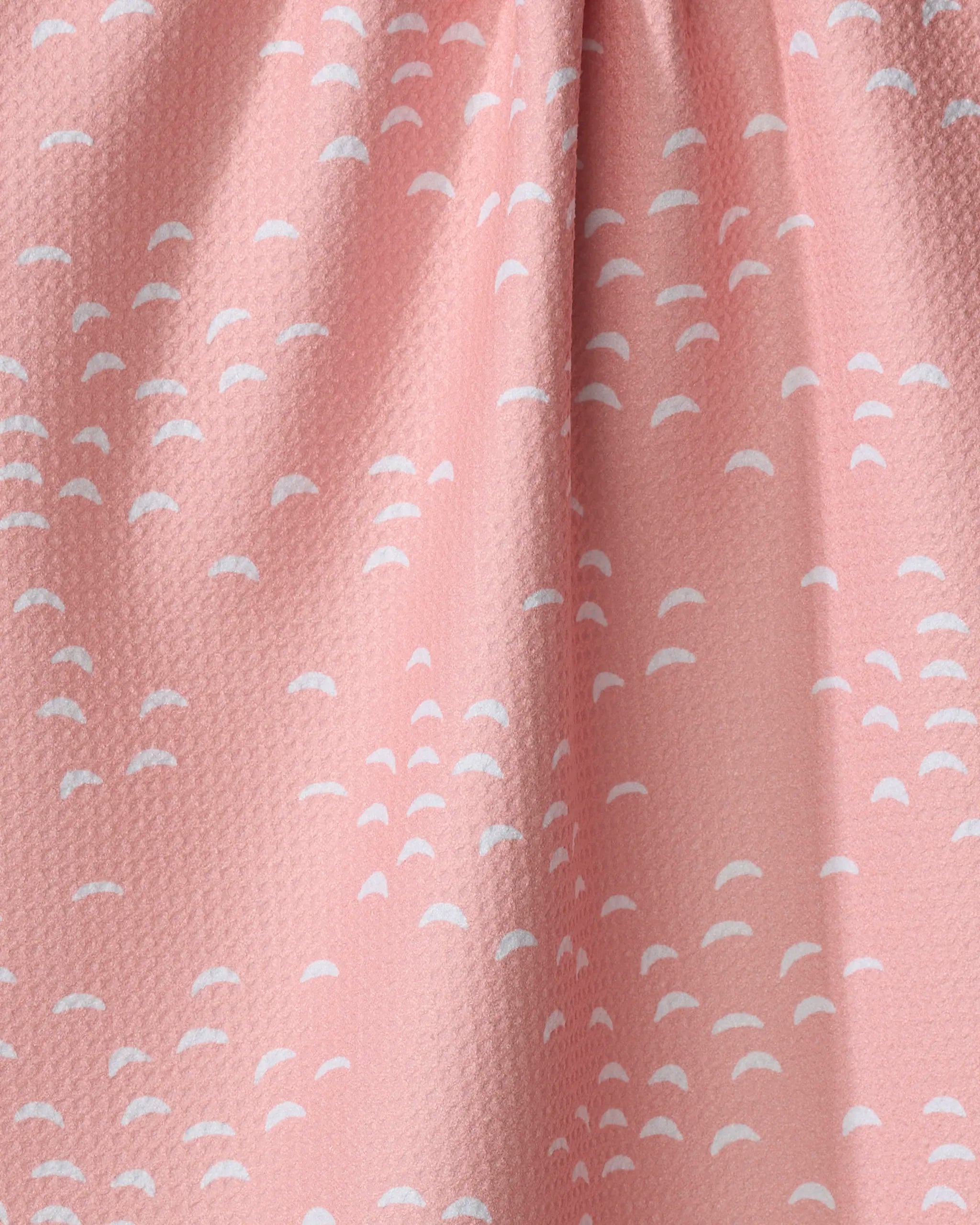 A close-up of Windswept by Jessica Swift shows a pink recycled kitchen towel with small white semi-circular shapes in clusters. The textured fabric is slightly gathered, creating gentle folds and soft shadows.